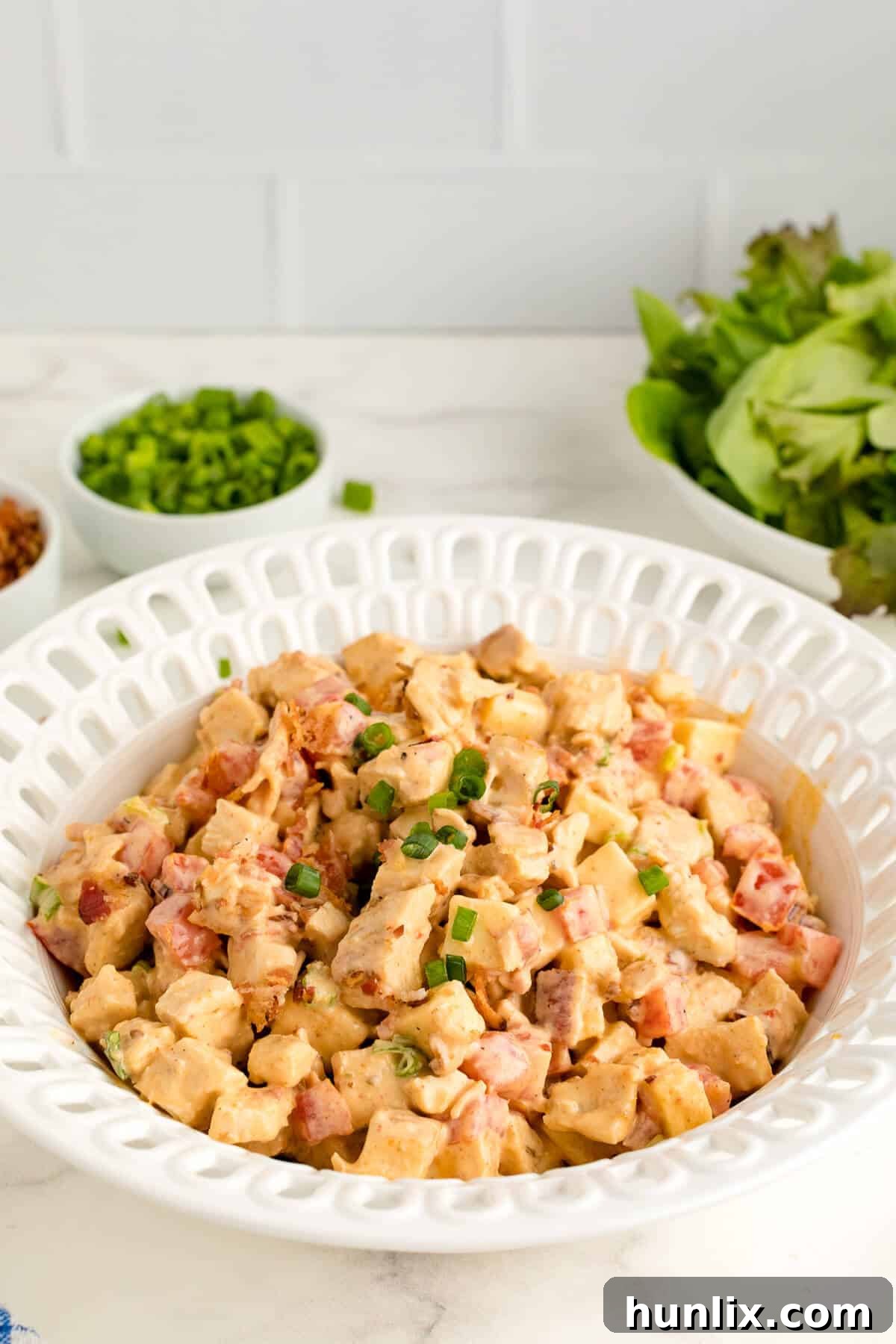 Crisp BLT Chicken Salad 2 Chicken BLT Salad in a white bowl, garnished with fresh greens.