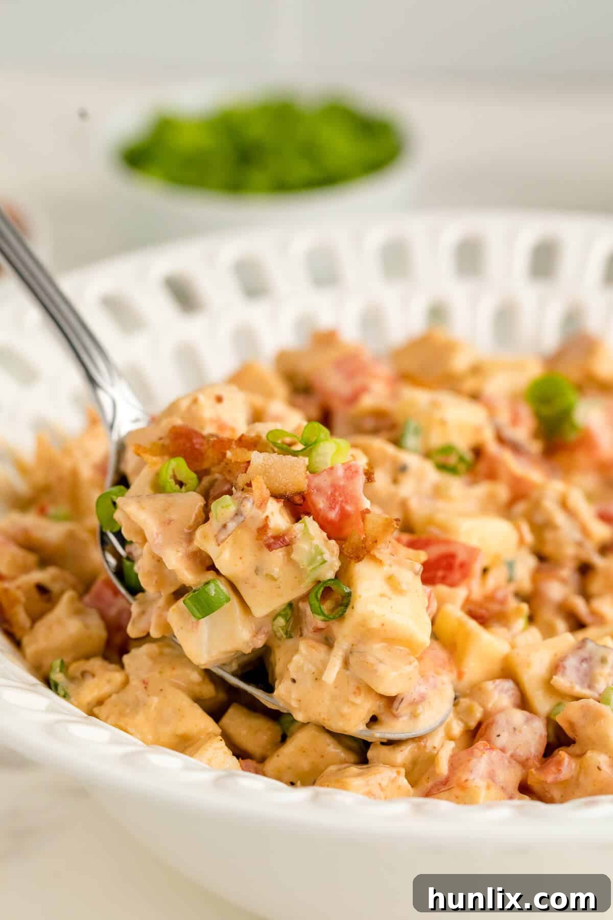 Crisp BLT Chicken Salad 3 Chicken BLT Salad served in a bowl with a large serving spoon, showing textures.