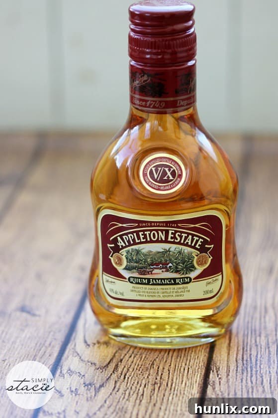 A beautifully crafted Appleton Estate Manhattan cocktail, garnished with an orange peel and a cherry, against a rustic background, highlighting its rich amber hue.