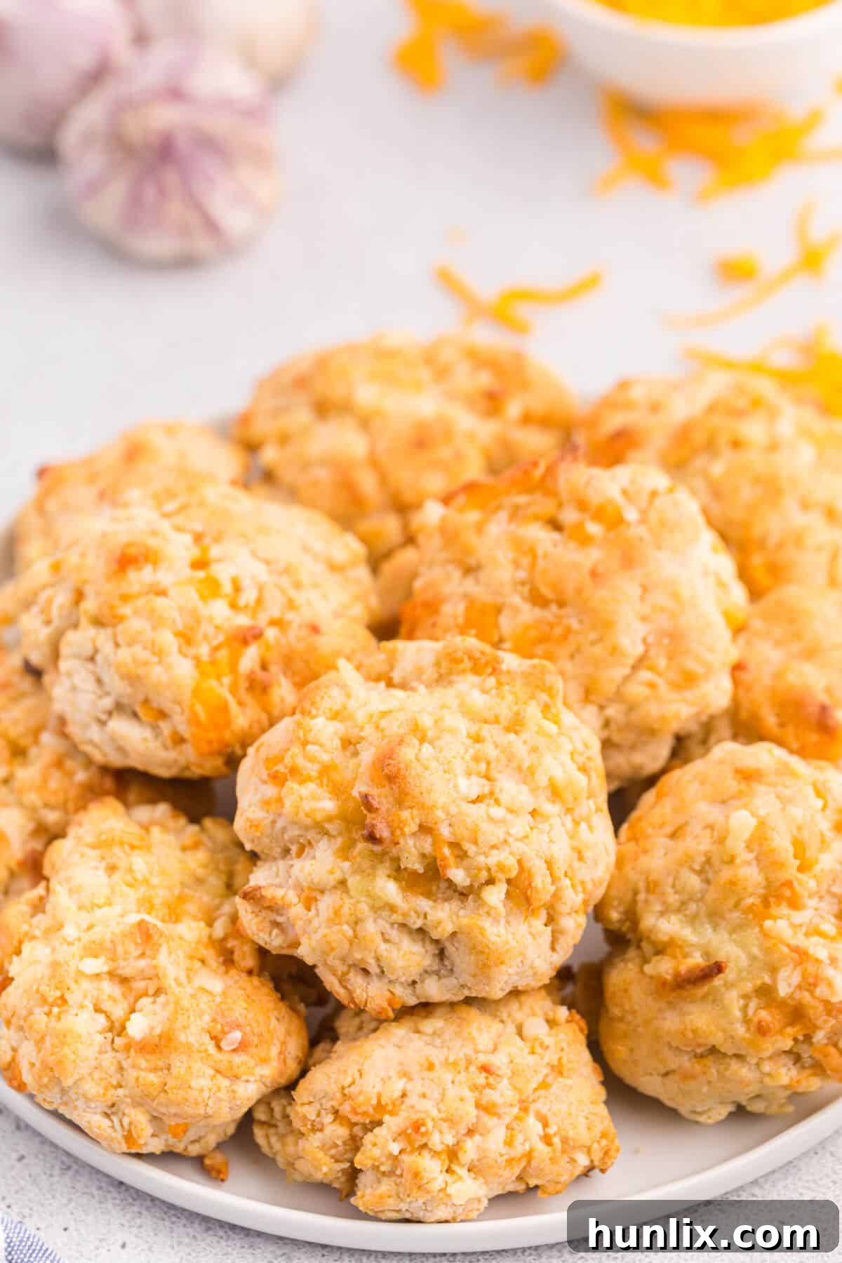 Buttery Garlic Cheese Biscuits 4 A plate of golden-brown cheesy garlic biscuits, with one cut in half revealing the melted cheese.