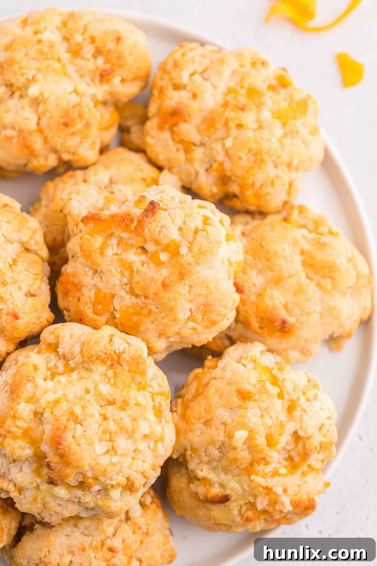 Buttery Garlic Cheese Biscuits 5 Two cheesy garlic biscuits on a plate, with a knife and a small bowl of melted garlic butter in the background.