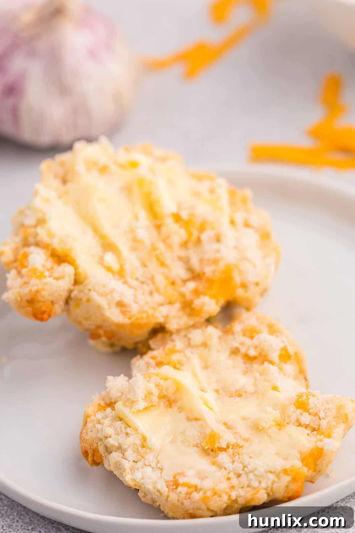 Buttery Garlic Cheese Biscuits 6 A cheesy garlic biscuit cut in half on a wooden board, showing its soft interior and melted cheese.