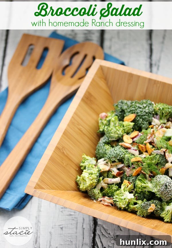 Close-up of the finished broccoli salad, showcasing the texture of fresh broccoli florets, golden raisins, sliced almonds, and bacon bits coated in a creamy dressing.