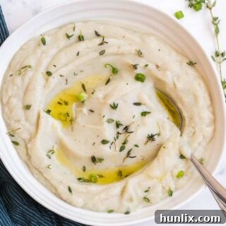 Creamy Vegan Cauliflower Mash 6 A close-up shot of creamy vegan mashed cauliflower in a white bowl with a serving spoon, highlighting its smooth texture and inviting appearance.