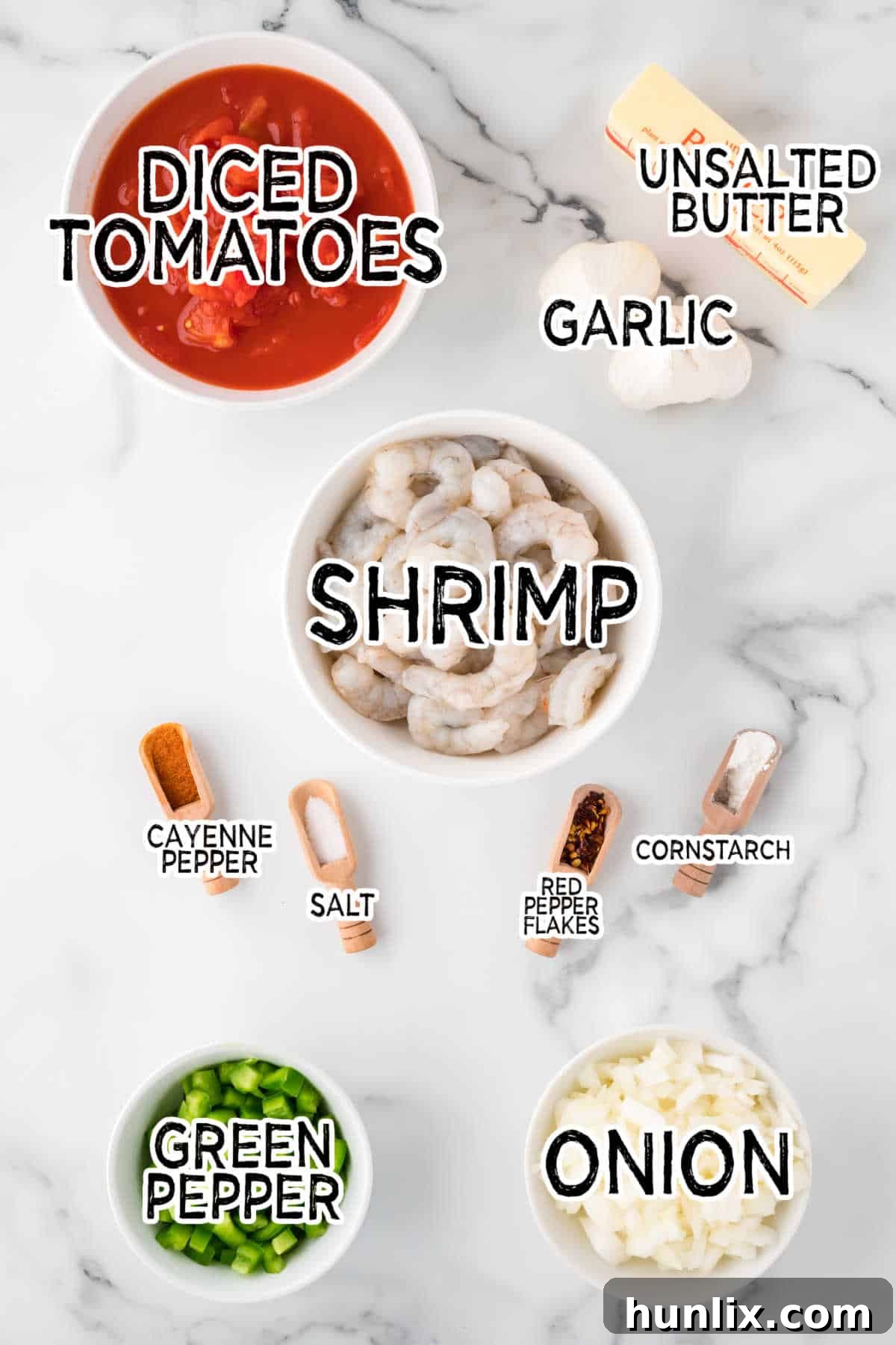 Fresh ingredients laid out on a marble counter, including shrimp, onions, bell peppers, butter, garlic, and spices, ready for making Shrimp Creole.