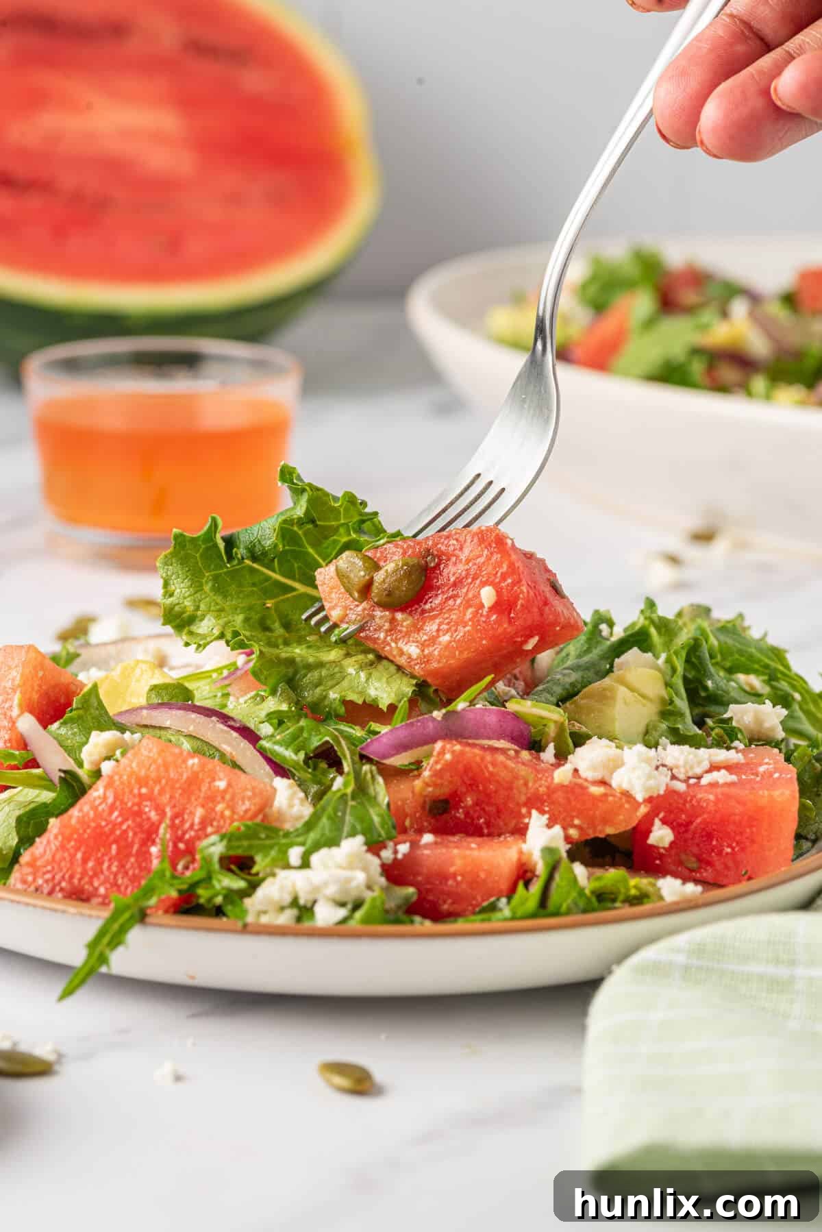 A close-up shot of a fork holding a perfect bite of Watermelon and Feta Salad, showcasing the crisp watermelon, creamy feta, and green avocado, ready to be eaten.