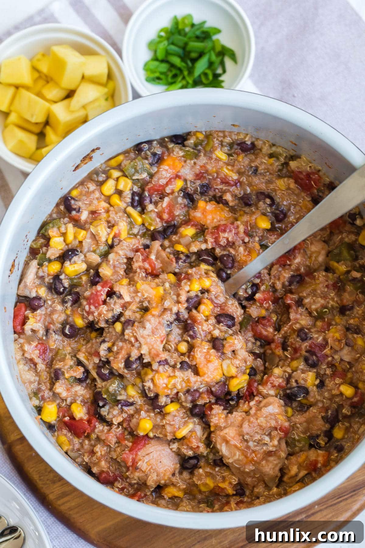 A large pot filled with a rich, colorful slow cooker chicken quinoa chili, with a ladle resting inside.