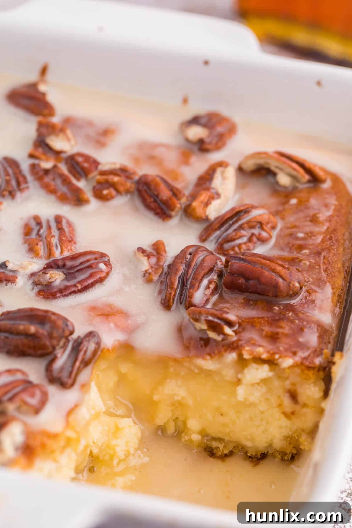 A maple pecan danish bake in a casserole dish with a generous slice already removed, showing the creamy filling layers.