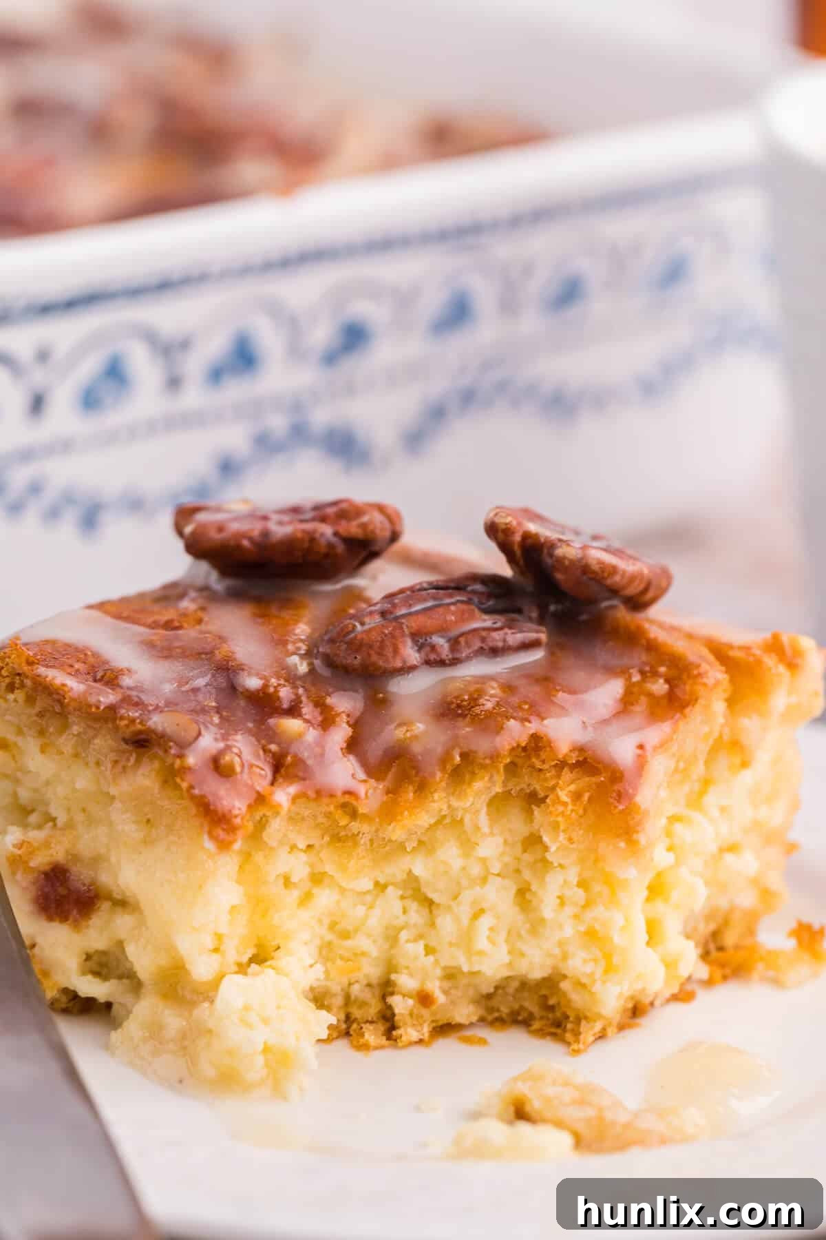 A slice of maple pecan danish bake on a plate with a fork taking a bite, showing the soft interior.