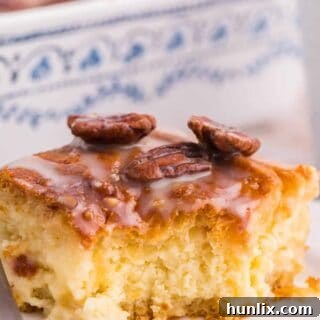 A piece of maple pecan danish bake on a plate with a bite taken out, showing the layers of dough and creamy filling.