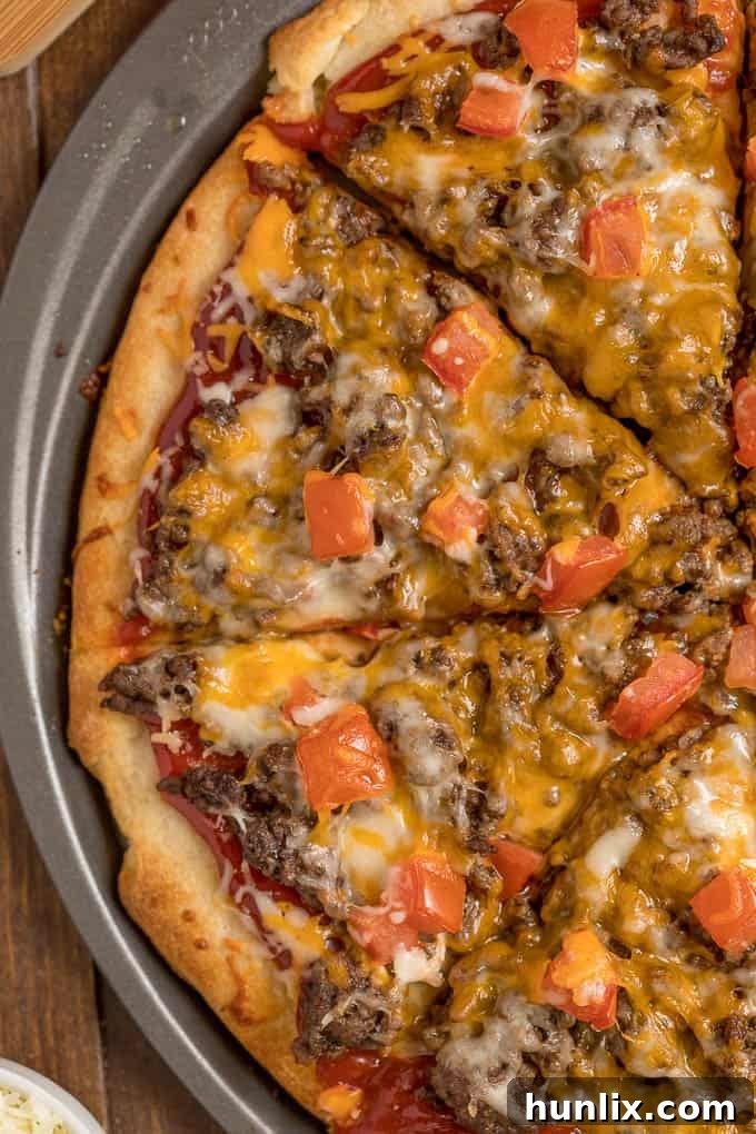Cheeseburger pizza with slices cut on a pizza pan.
