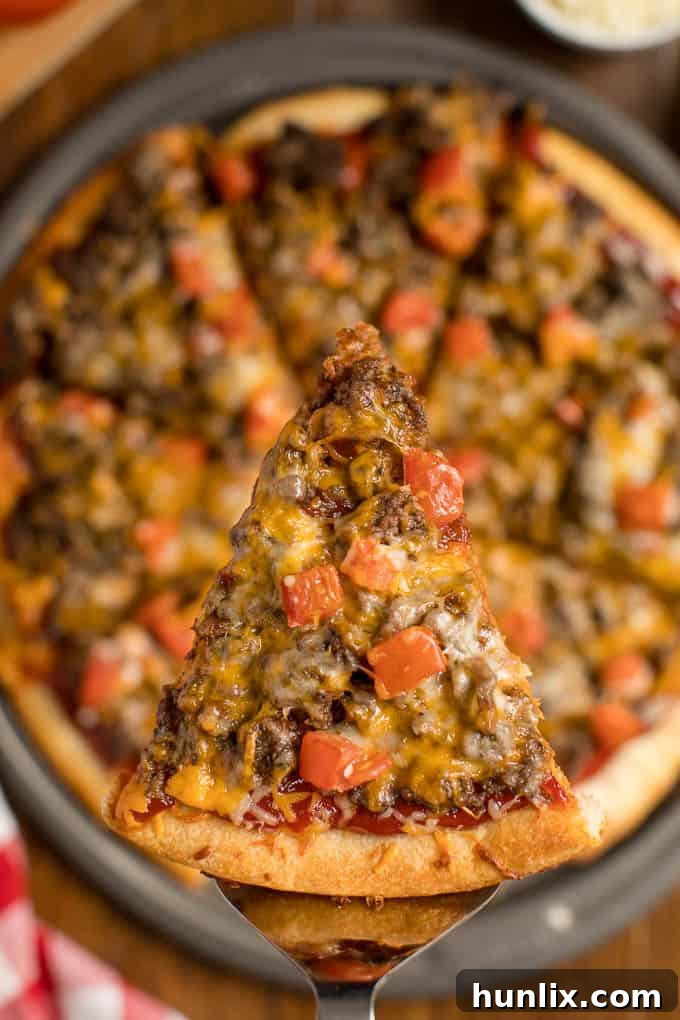 A slice of cheeseburger pizza on a serving spatula.