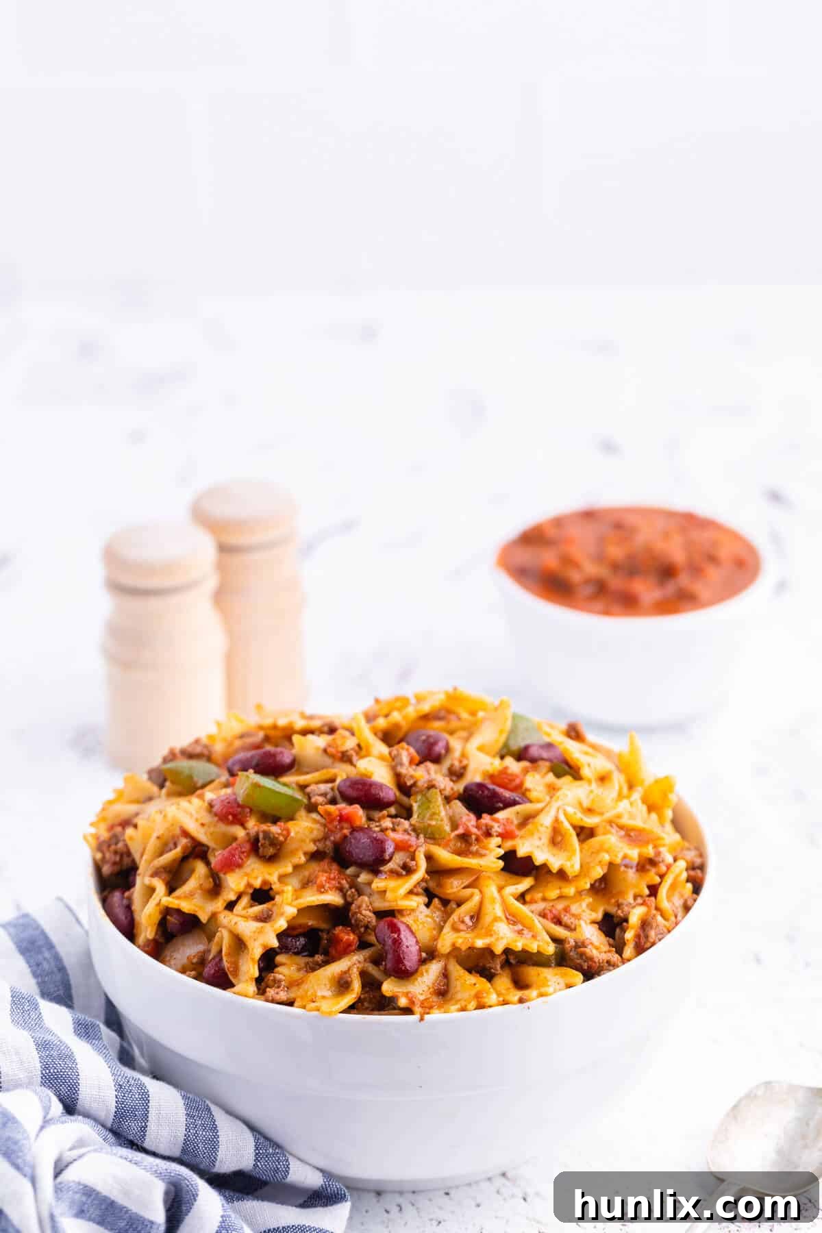 Close-up of Chili Pasta Salad in a white ceramic bowl, highlighting the texture of the bowtie pasta, ground beef, and colorful vegetables.