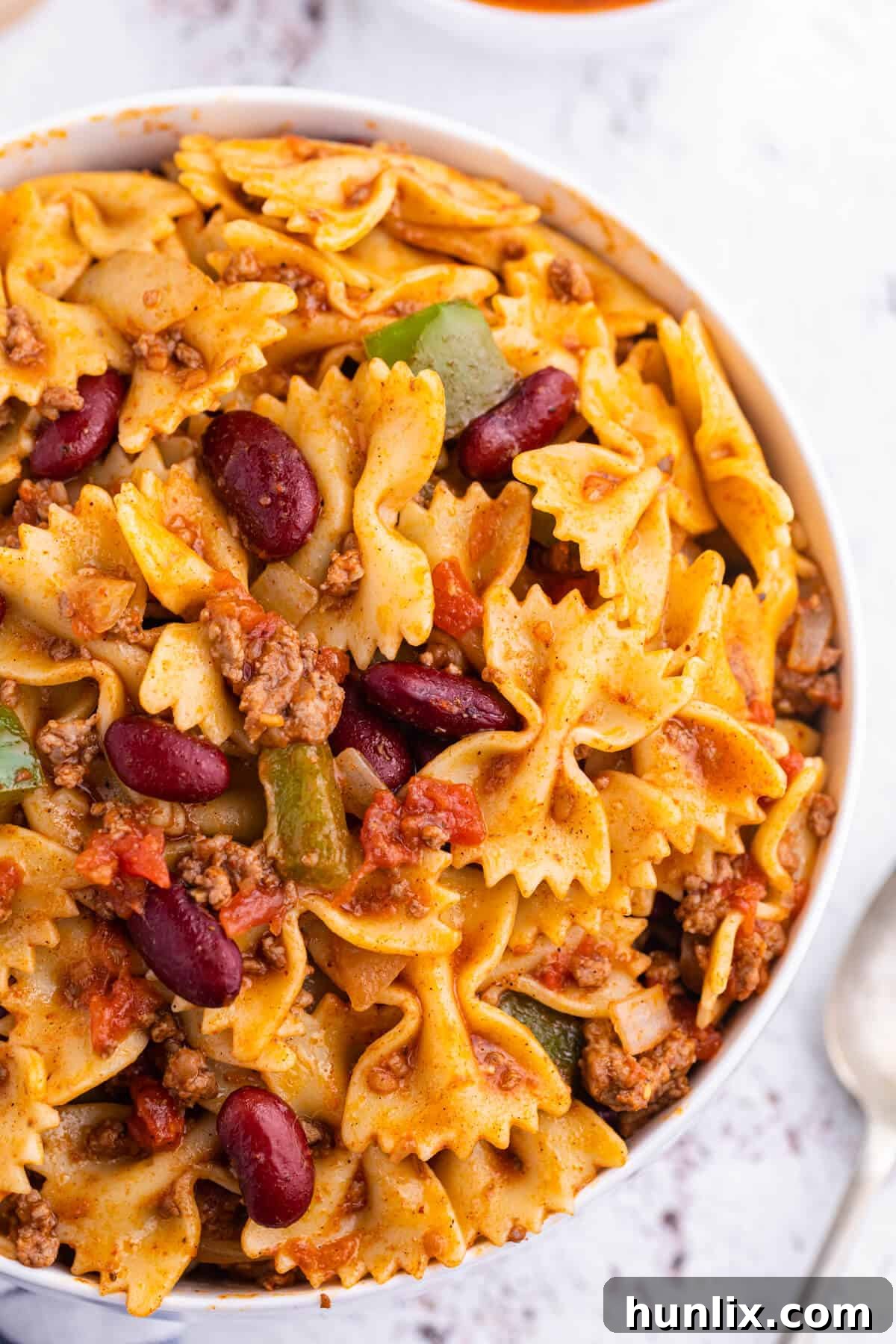 Overhead shot of Chili Pasta Salad in a decorative bowl, emphasizing the inviting composition and a serving spoon placed within.