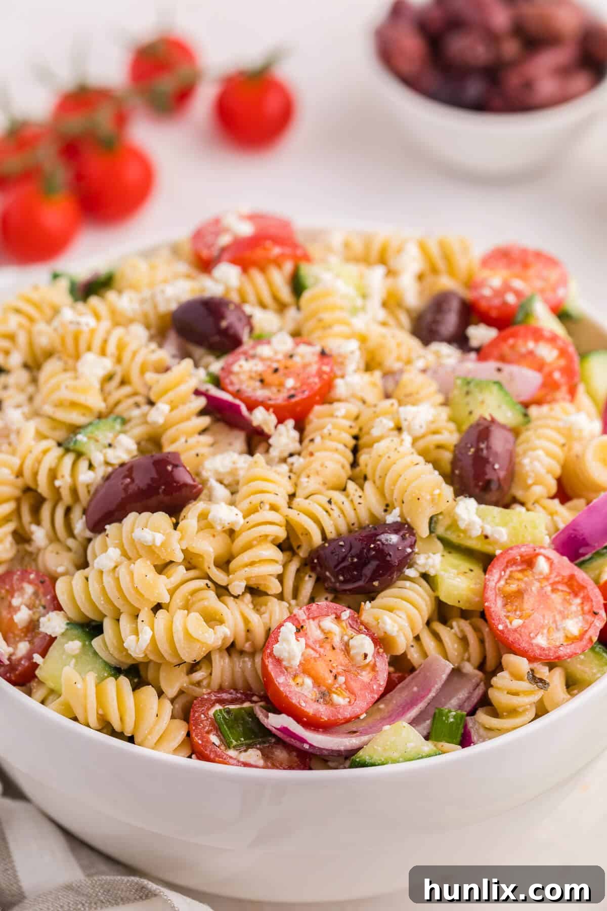 Zesty Greek Pasta Medley 8 A large bowl of Greek pasta salad, showcasing the colorful mix of pasta, olives, tomatoes, cucumbers, and feta cheese, ready for serving or storage.