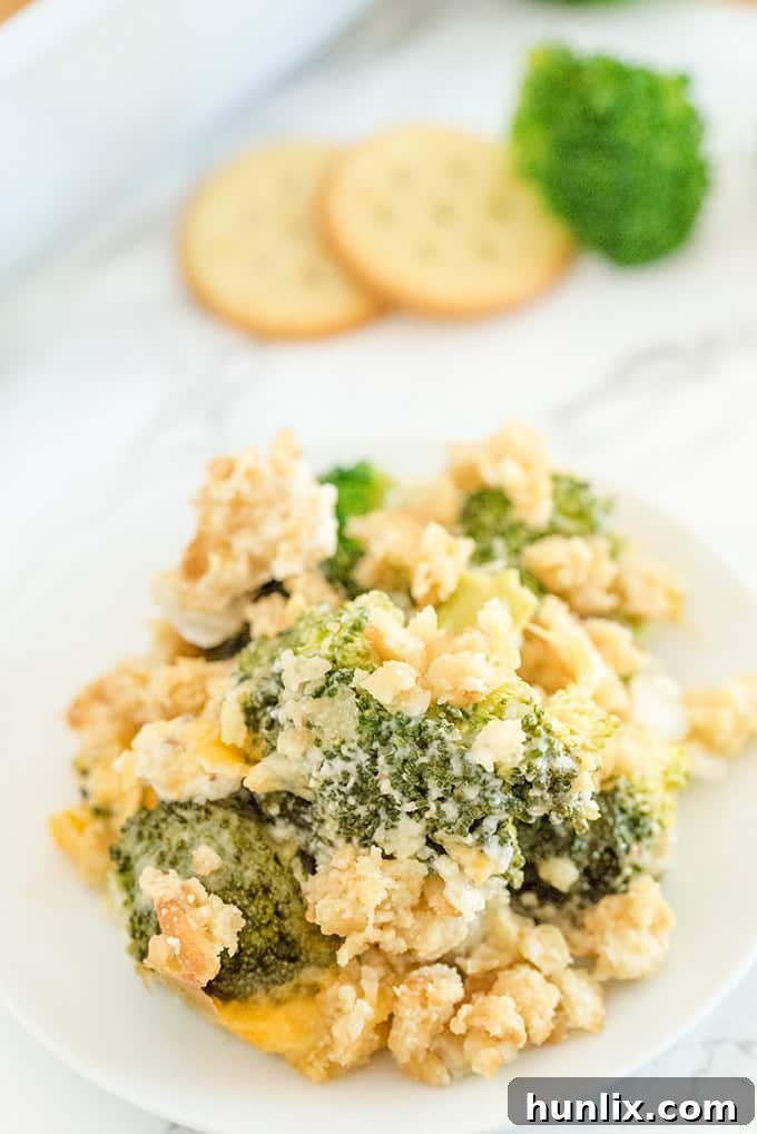 A single serving of broccoli casserole on a white plate, showcasing the creamy filling and crispy cracker topping.