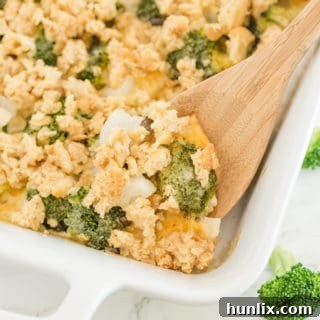 The finished broccoli casserole in a white baking dish with a wooden serving spoon.