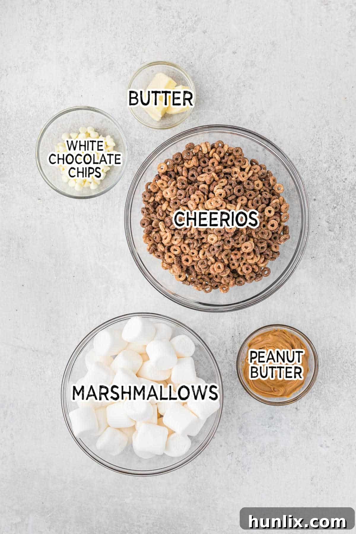 No Bake White Chocolate Peanut Butter Cheerios Squares 3 A flat lay of ingredients for white chocolate peanut butter Cheerios treats, including butter, marshmallows, Cheerios, peanut butter, and white chocolate chips.
