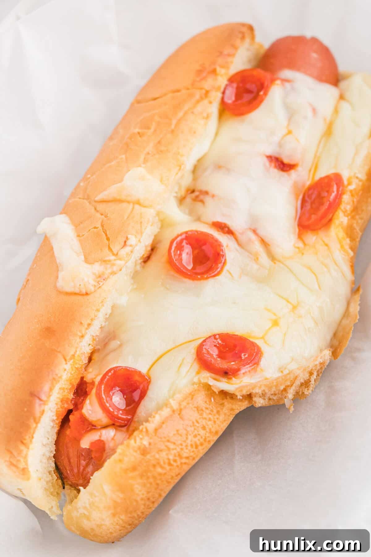 Pizzadog 6 A perfectly baked pizza hot dog presented on a simple white plate.