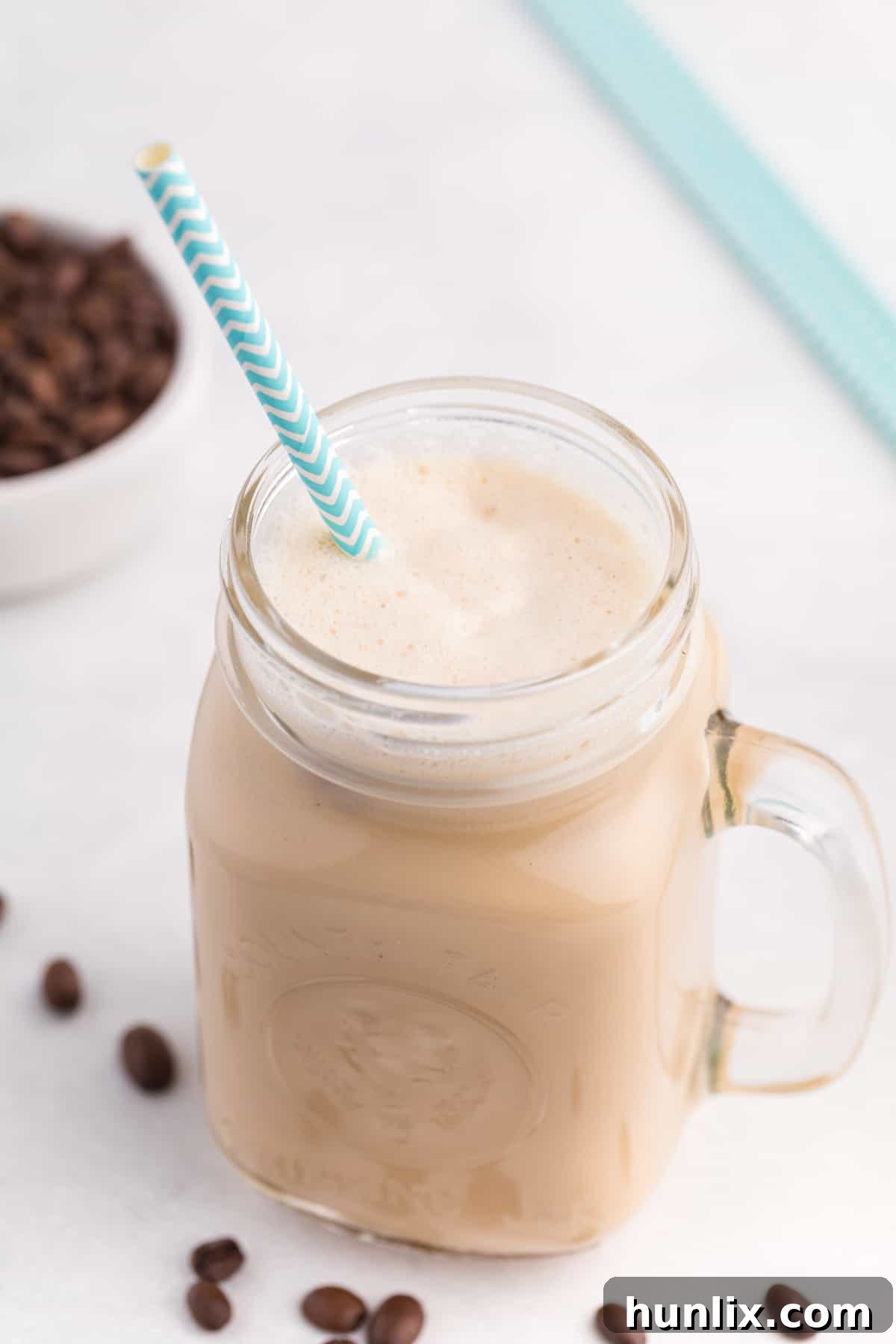 The finished iced coffee drink in a stylish glass with a straw, ready to be enjoyed.