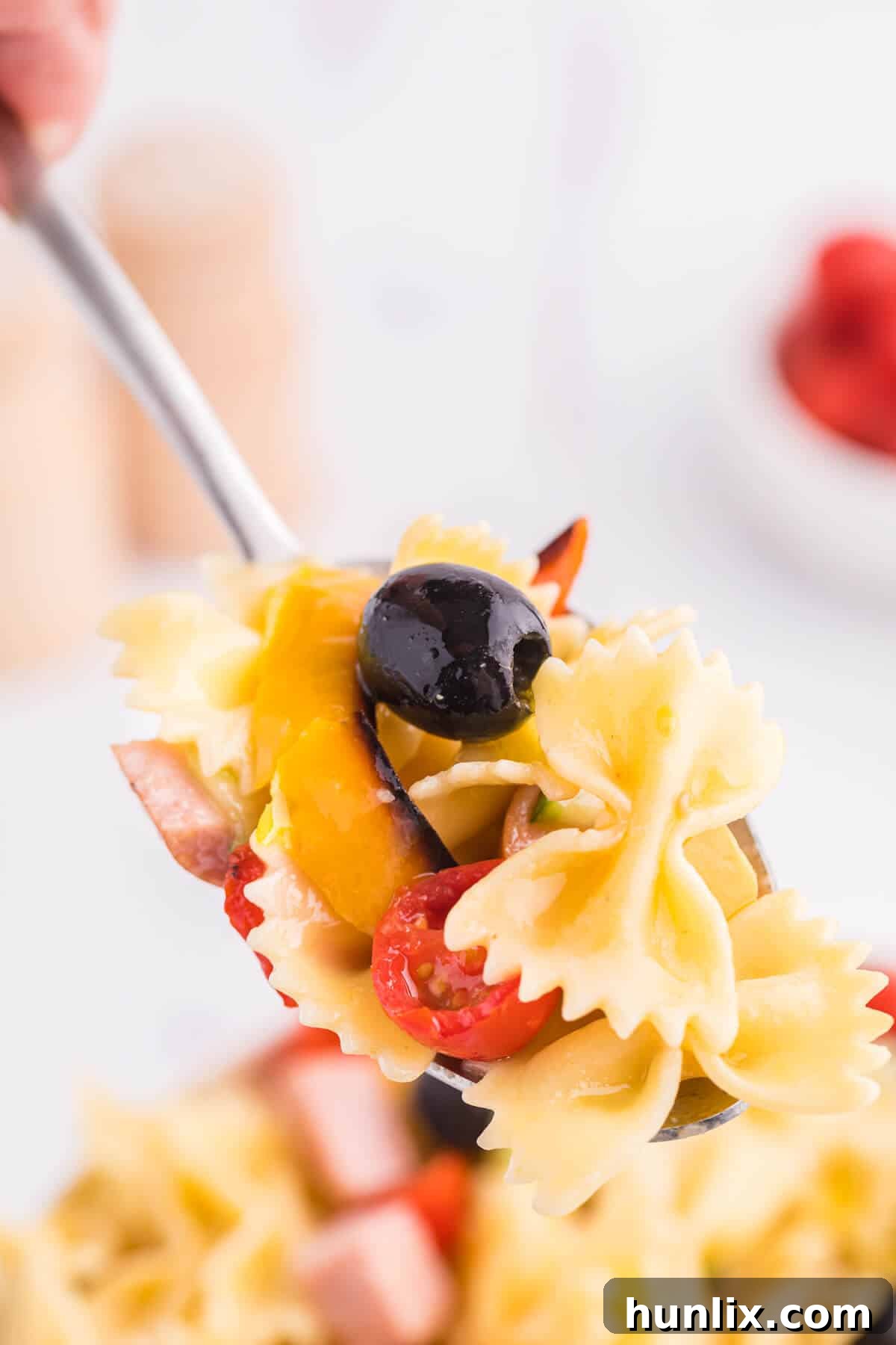 Blistered Bell Pepper Pasta Toss 6 A serving spoon lifting roasted pepper pasta salad from a bowl.