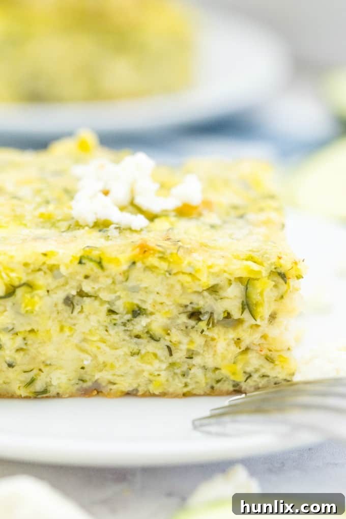 A serving of Cheesy Zucchini Bake alongside a cooked meat dish, showing it as a perfect side.