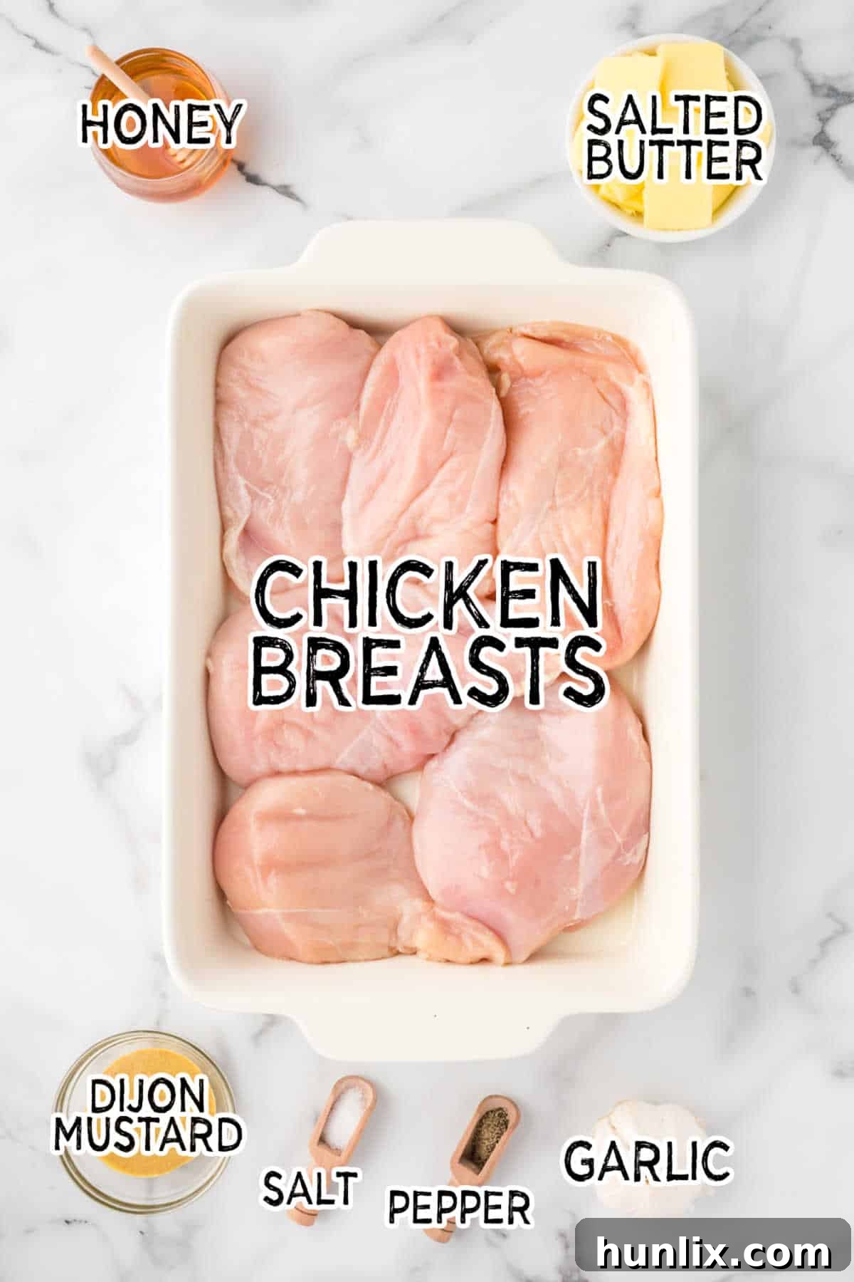 Golden Honey Garlic Chicken 3 A selection of fresh ingredients including honey, butter, garlic, and Dijon mustard on a white marble counter, ready for cooking.