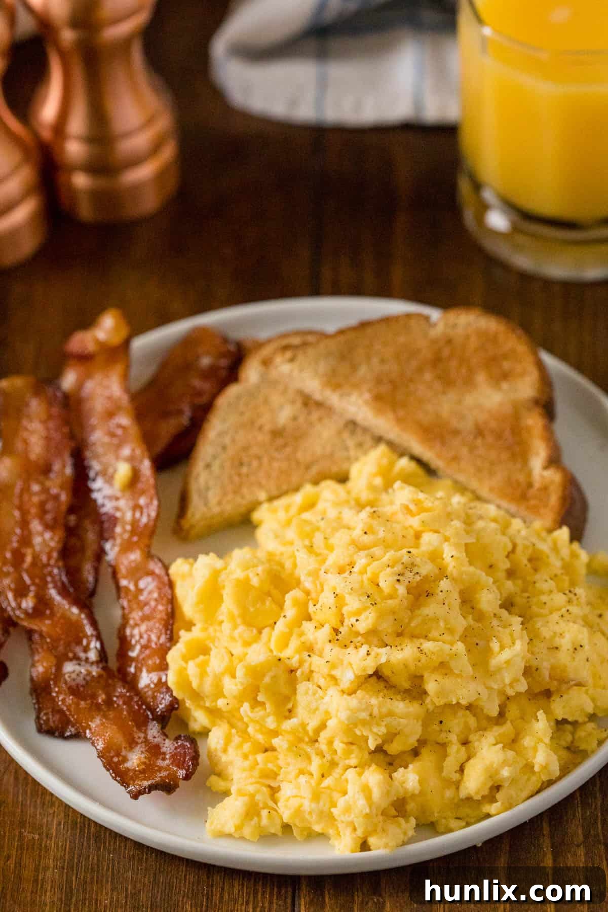 A plate of fluffy oven scrambled eggs served with crispy bacon and buttered toast, ready for a delicious breakfast.