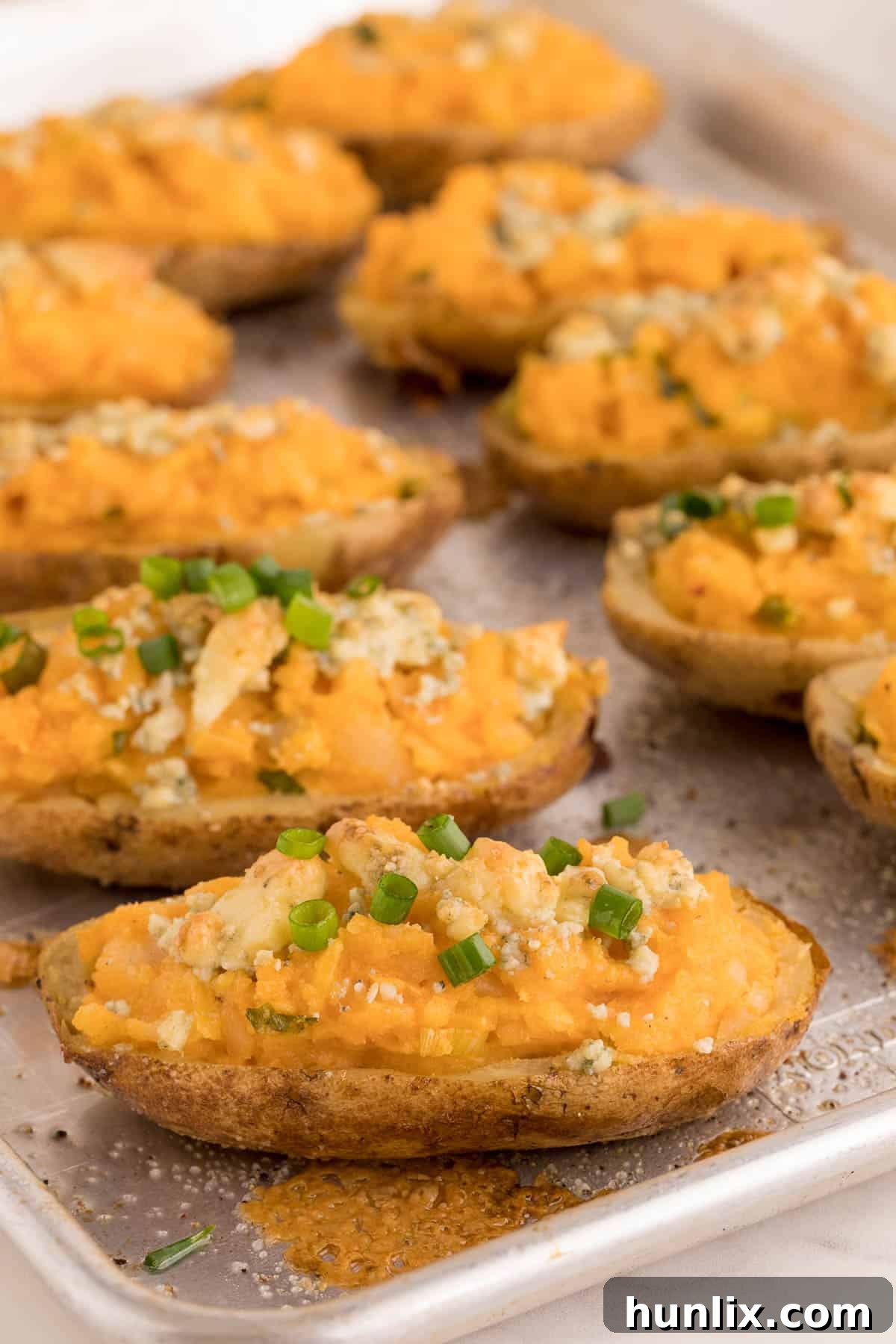 Buffalo Stuffed Potatoes 2 Buffalo Twice Baked Potatoes on a sheet pan, showcasing their golden-brown skins and cheesy topping, ready for serving.
