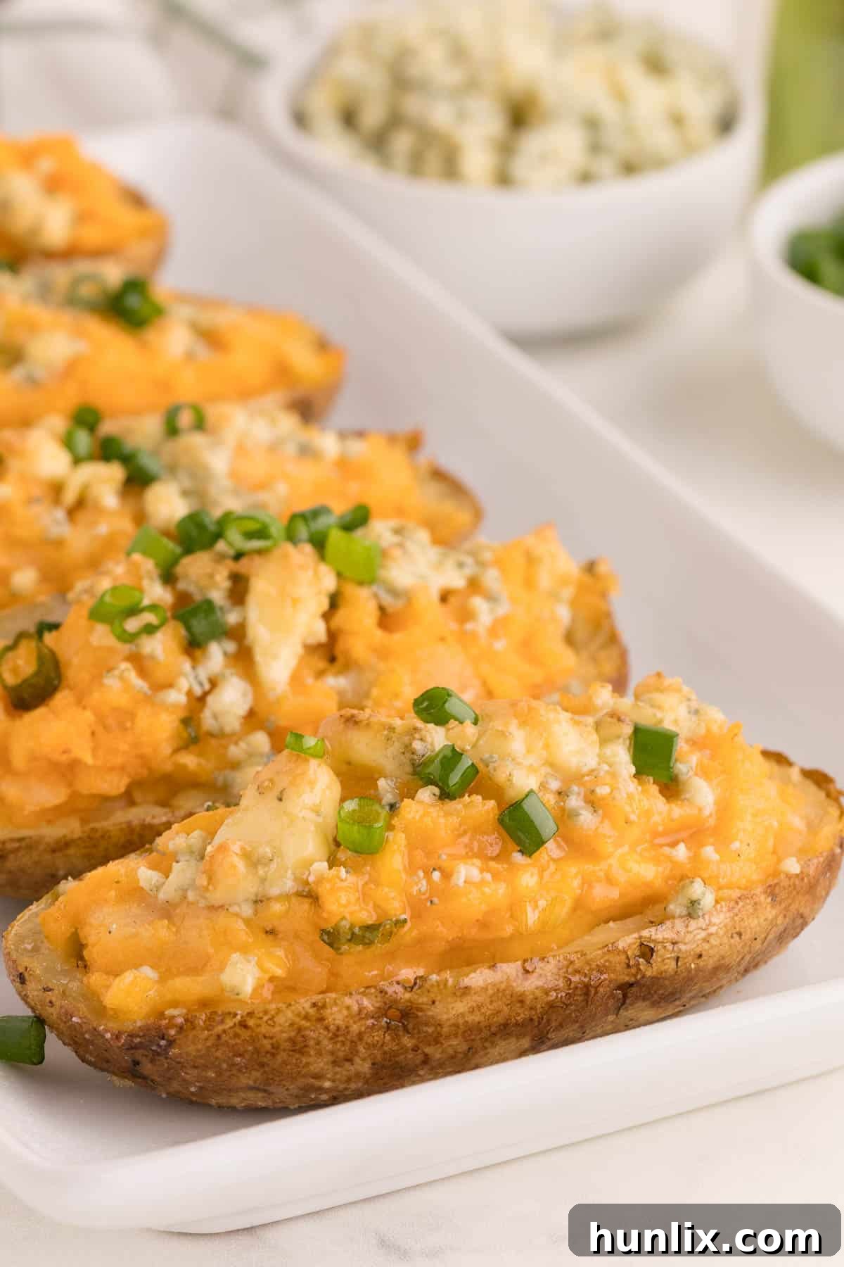 Buffalo Stuffed Potatoes 4 Buffalo Twice-Baked Potatoes neatly arranged on a white platter, highlighting the golden skins and cheesy topping.