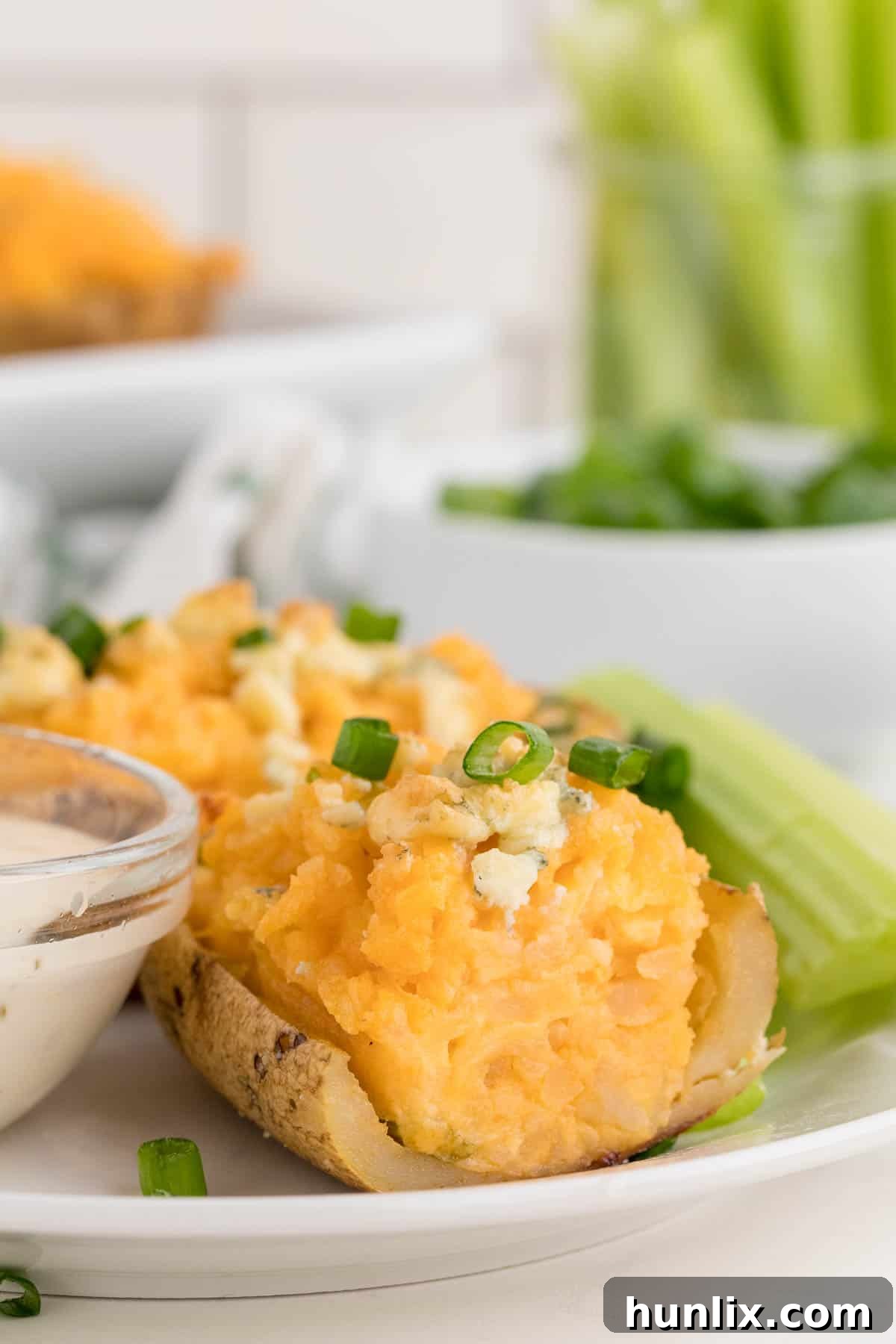 Buffalo Stuffed Potatoes 5 A perfectly sliced Buffalo Twice-Baked Potato on a plate, revealing its creamy, cheesy interior with buffalo sauce swirls.