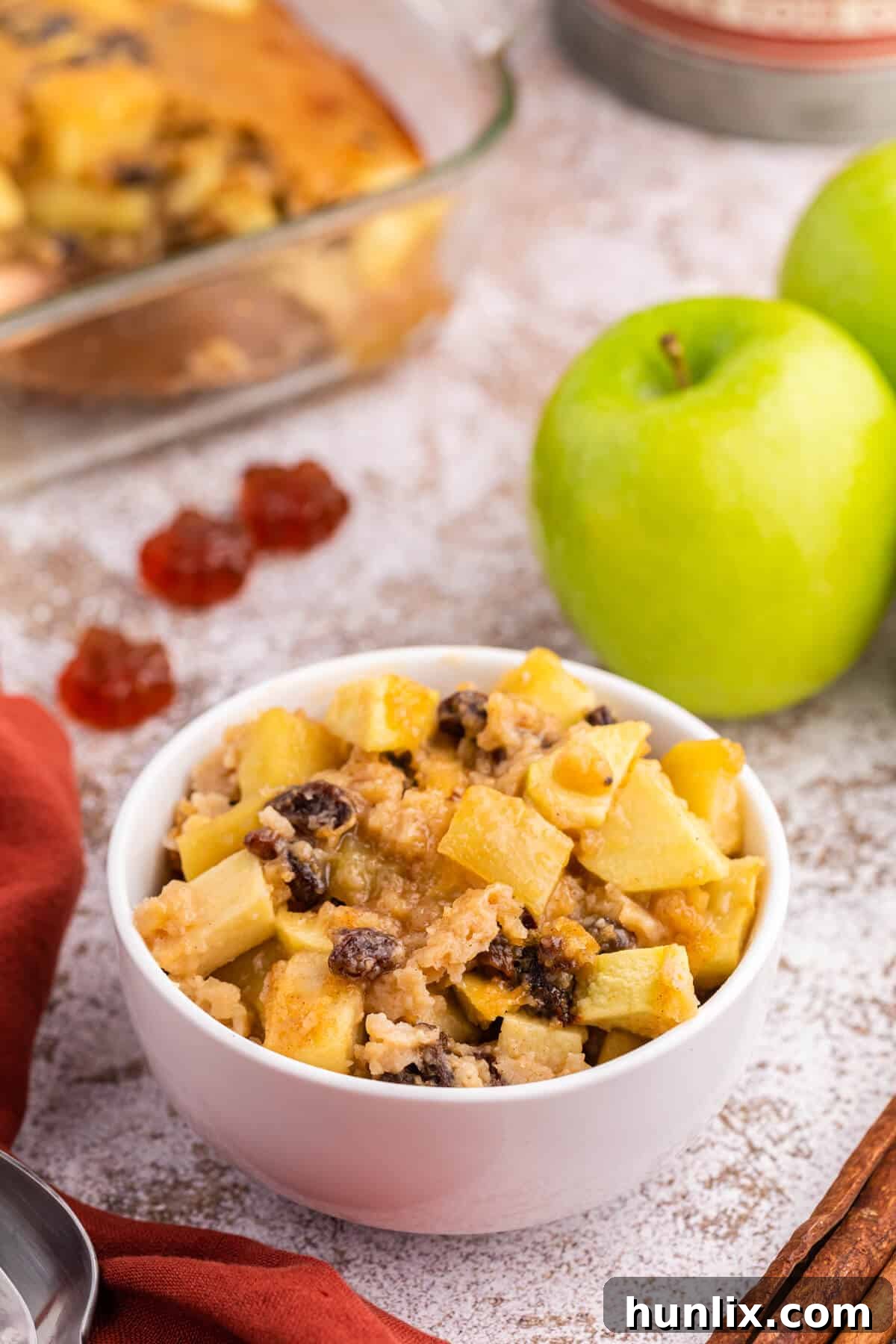 A bowl of maple apple pudding topped with a scoop of vanilla ice cream, garnished with a sprinkle of cinnamon.