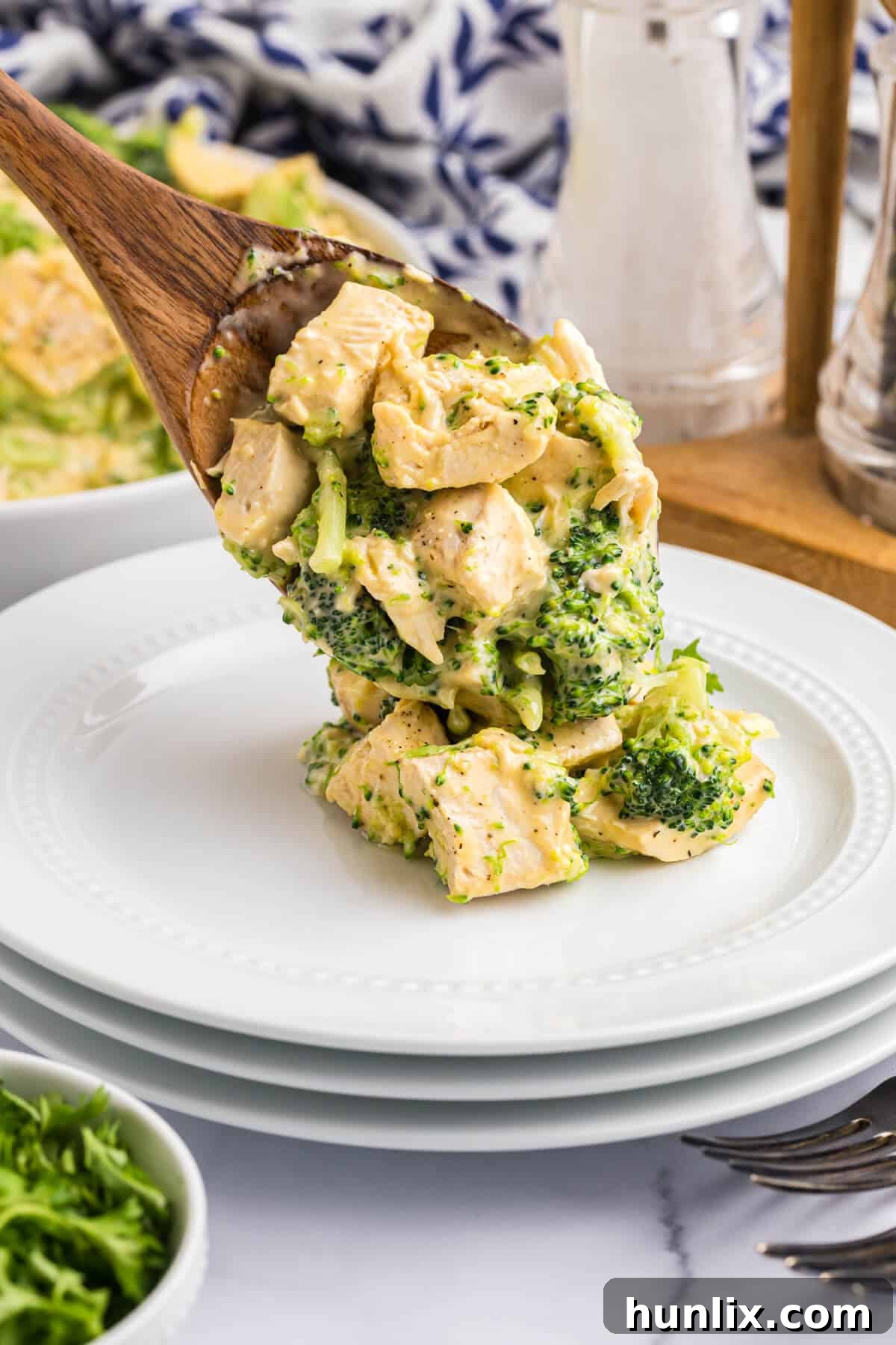 Ultimate Cheesy Chicken Broccoli Bake 6 Cheesy chicken and broccoli on a wooden serving spoon.
