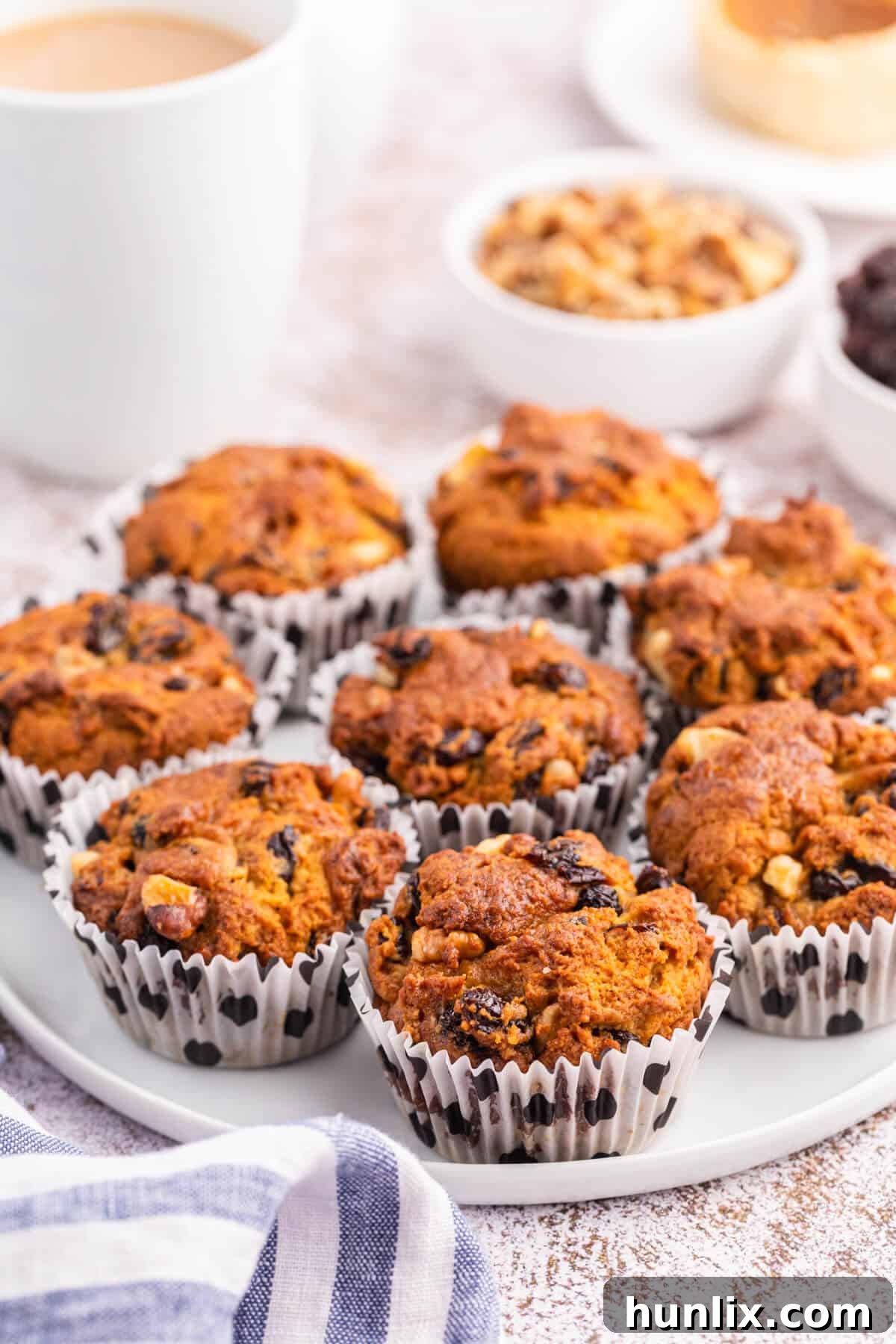 Golden Butter Tart Muffins 4 A single Butter Tart Muffin, sliced in half, revealing its moist interior, plump raisins, and crunchy walnuts, served on a white plate.