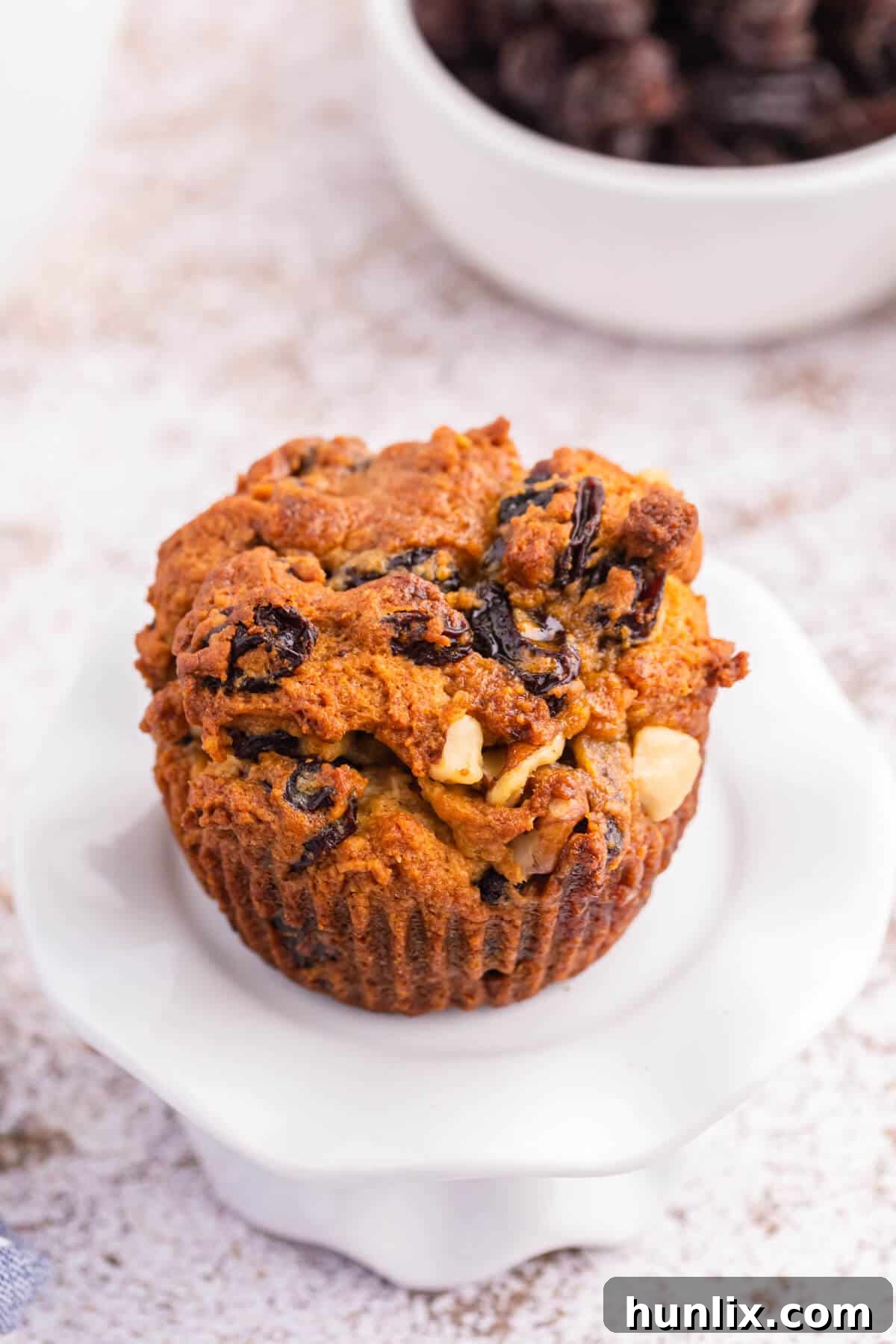 Golden Butter Tart Muffins 5 A perfectly baked Butter Tart Muffin sitting on a delicate white cupcake stand, ready to be enjoyed.