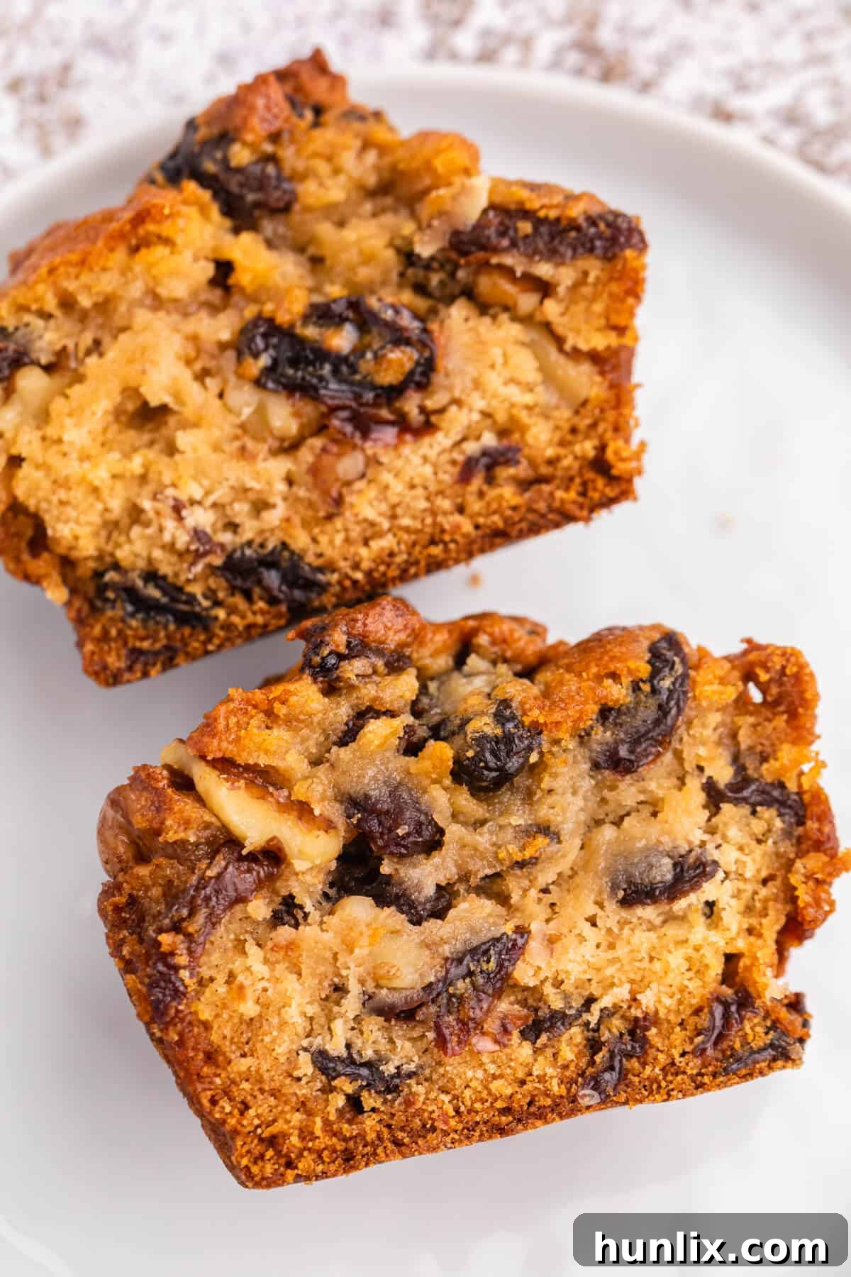 Golden Butter Tart Muffins 6 A Butter Tart Muffin neatly cut in half, showcasing its inviting golden crust and the gooey, raisin-filled center, served on a white plate.