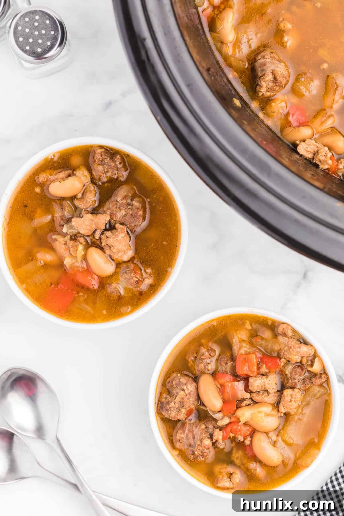 Robust Chicken and Sausage Stew 4 Various ingredients for Chicken and Sausage Soup laid out on a kitchen counter: ground chicken, Italian sausage, fresh vegetables, beer bottle, and spices