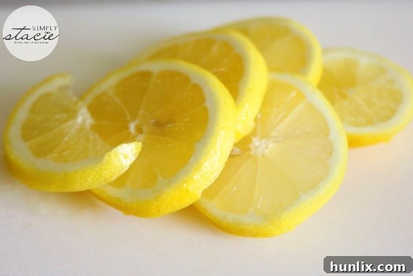 Choosing Your Vinegar for Microwave Cleaning: A bowl containing water and lemon slices, with a bottle of white wine vinegar in the background, demonstrating flexibility in ingredient choice.