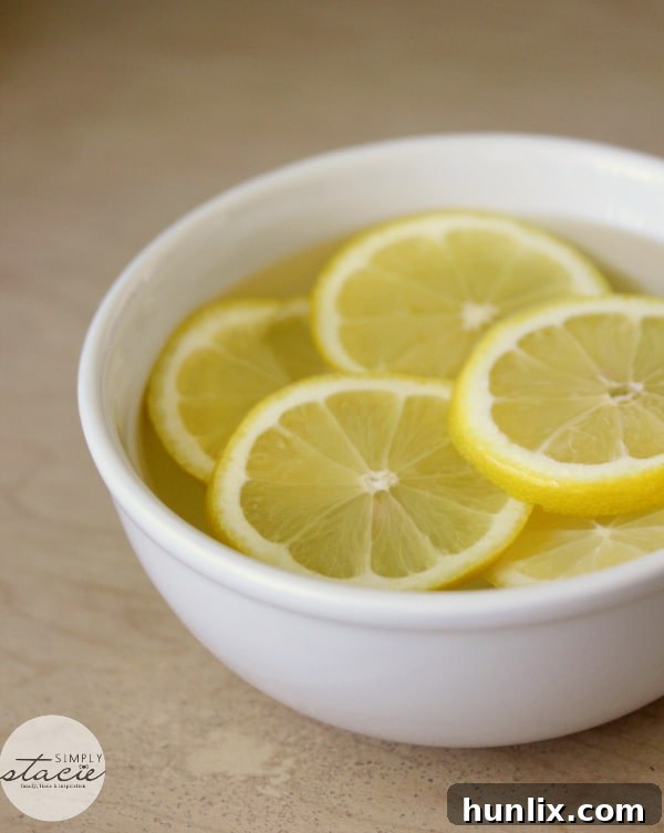 Preparing the Natural Microwave Cleaning Solution: A microwave-safe bowl filled with water, fresh lemon slices, and a splash of vinegar, showing the simple mixture before heating.
