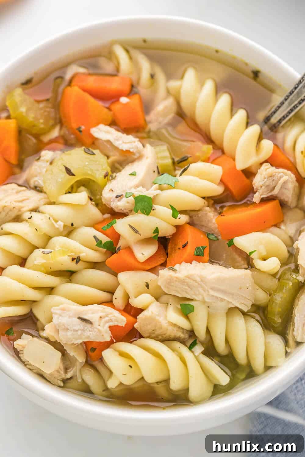 Grandma's Golden Chicken Noodle Soup 8 Close-up view of a rich bowl of homemade chicken noodle soup, highlighting the tender chicken, vegetables, and noodles.