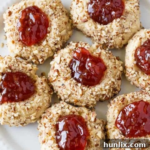 Classic jam-filled thumbprint cookies dusted with powdered sugar, a perfect holiday treat.