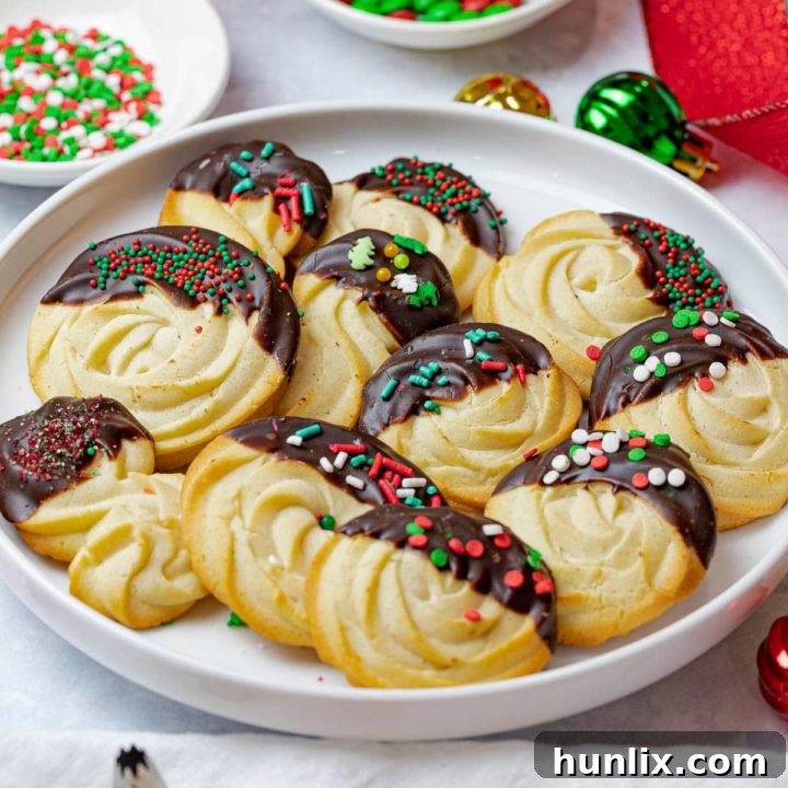 Easy Christmas butter cookies, dipped in chocolate and decorated with festive sprinkles.