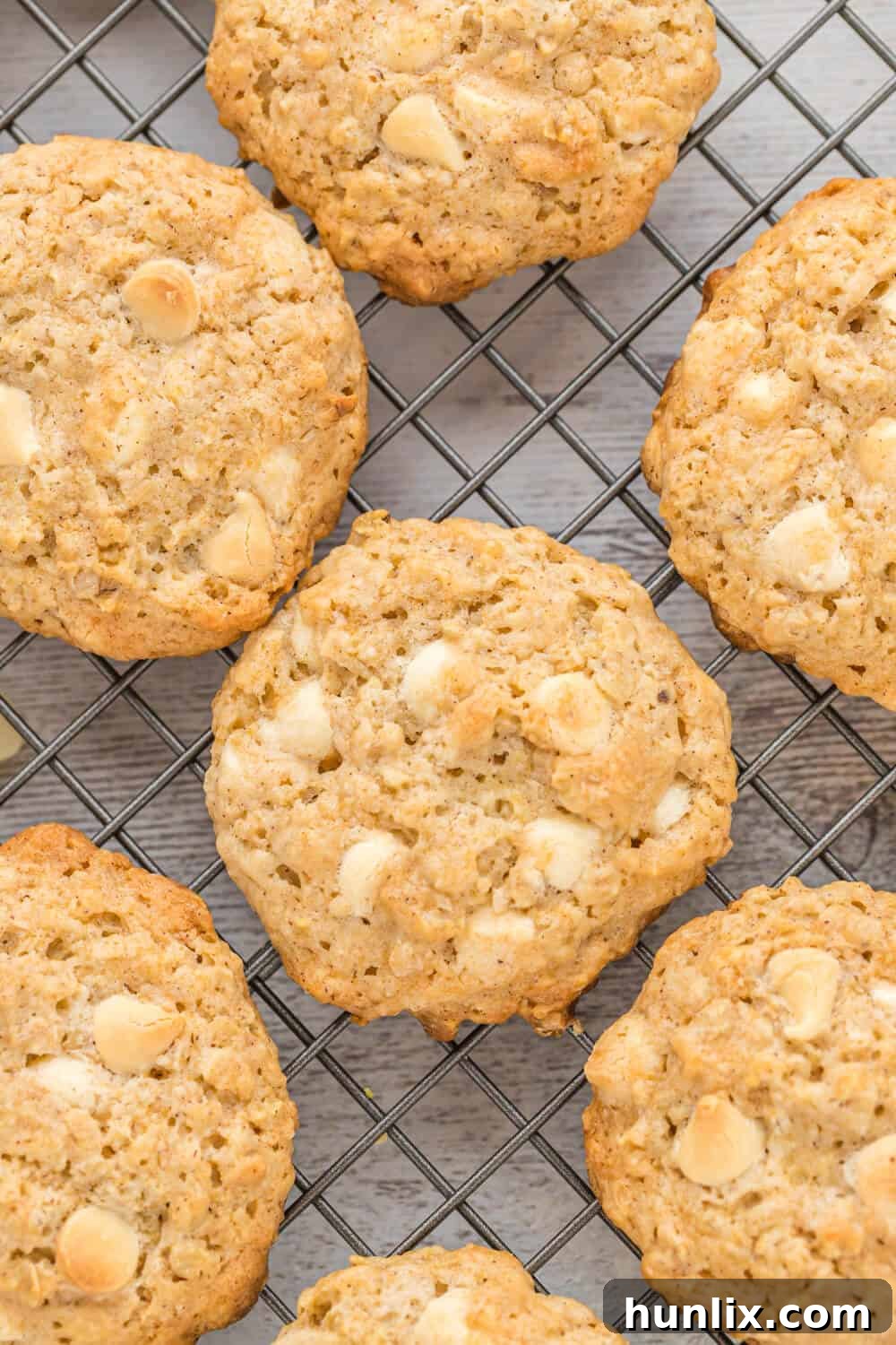 Freshly baked white chocolate oatmeal cookies cooling on a wire rack, showcasing their golden brown edges and visible white chocolate chips.