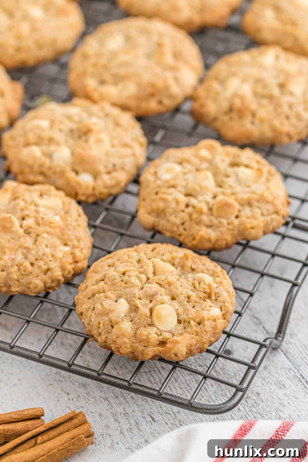 A generous pile of white chocolate oatmeal cookies neatly stacked on a cooling rack, showing their golden color and inviting texture.