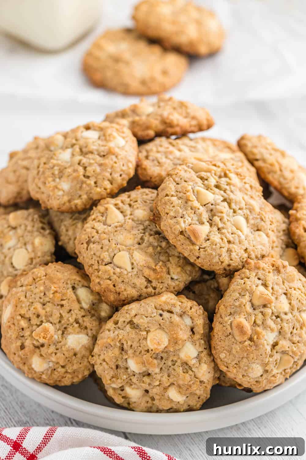 Several white chocolate oatmeal cookies attractively arranged on a simple white plate, ready to be served.
