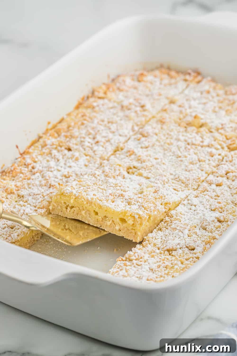 French vanilla cream bars in a baking pan with a spatula serving a piece.