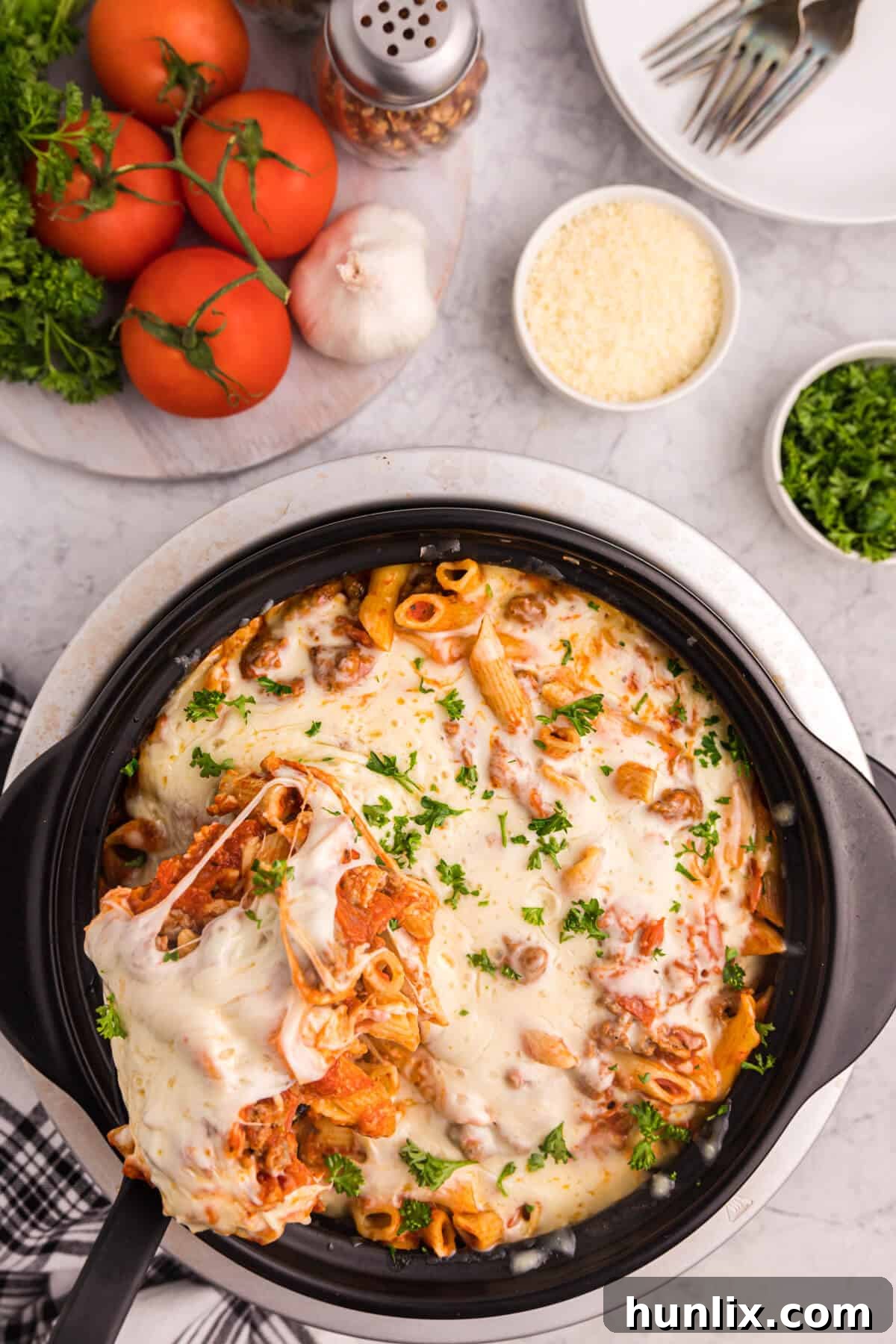 Slow cooker pizza pasta with a serving spoon in the crockpot, showcasing the creamy texture and delicious toppings.
