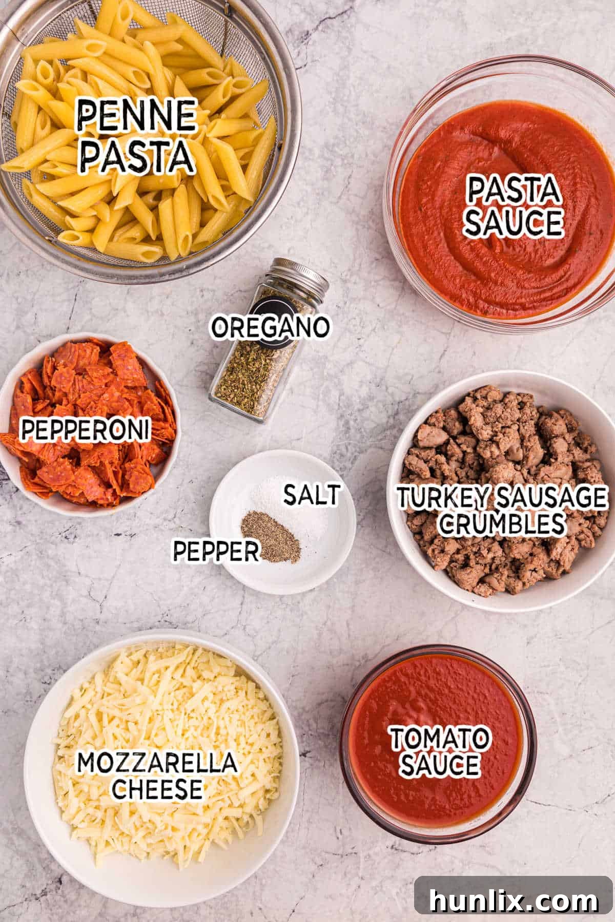 Collection of fresh ingredients for slow cooker pizza pasta, including pasta, sauces, cheeses, and seasonings.