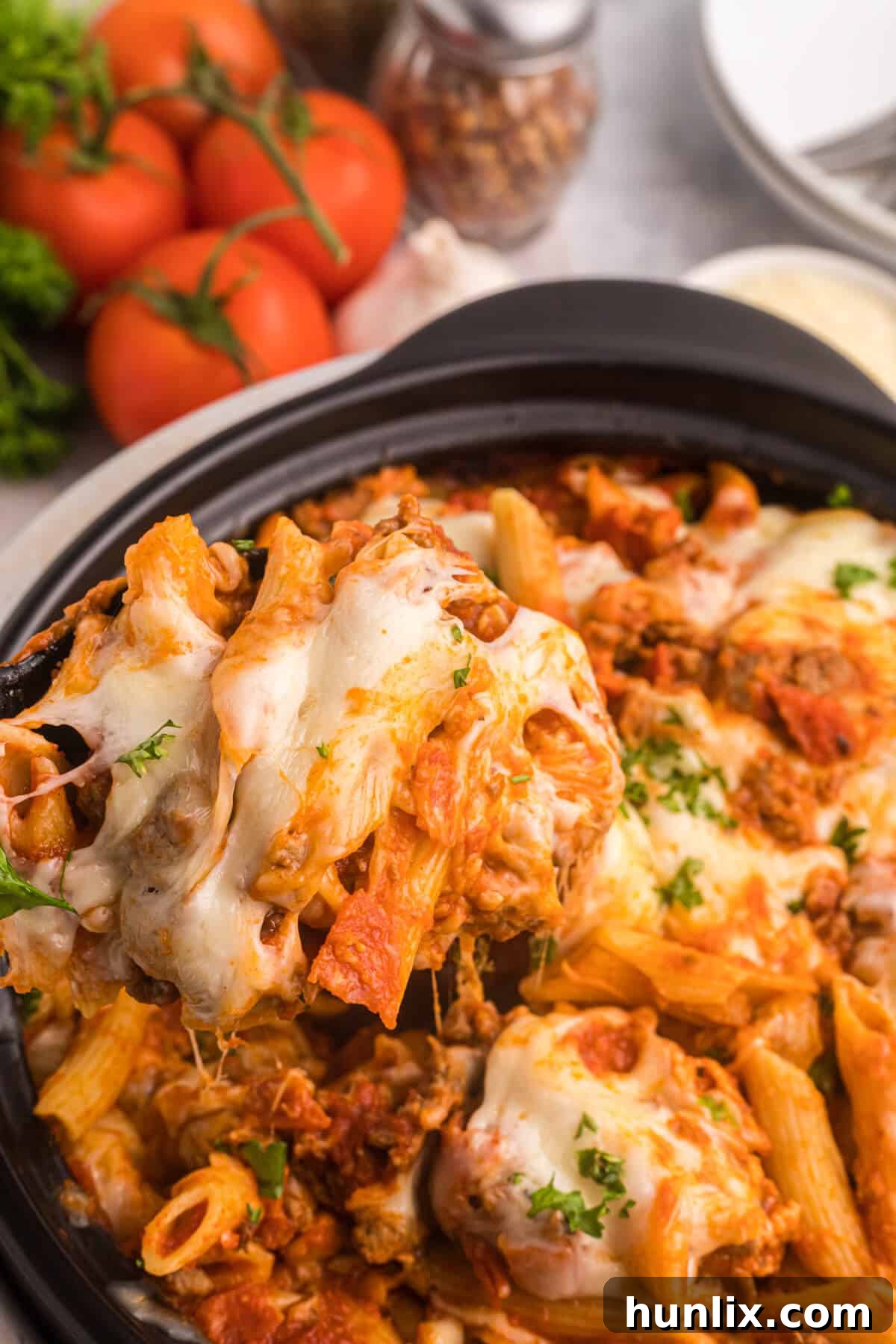 Slow cooker pizza pasta being served from the crockpot with a spoon.