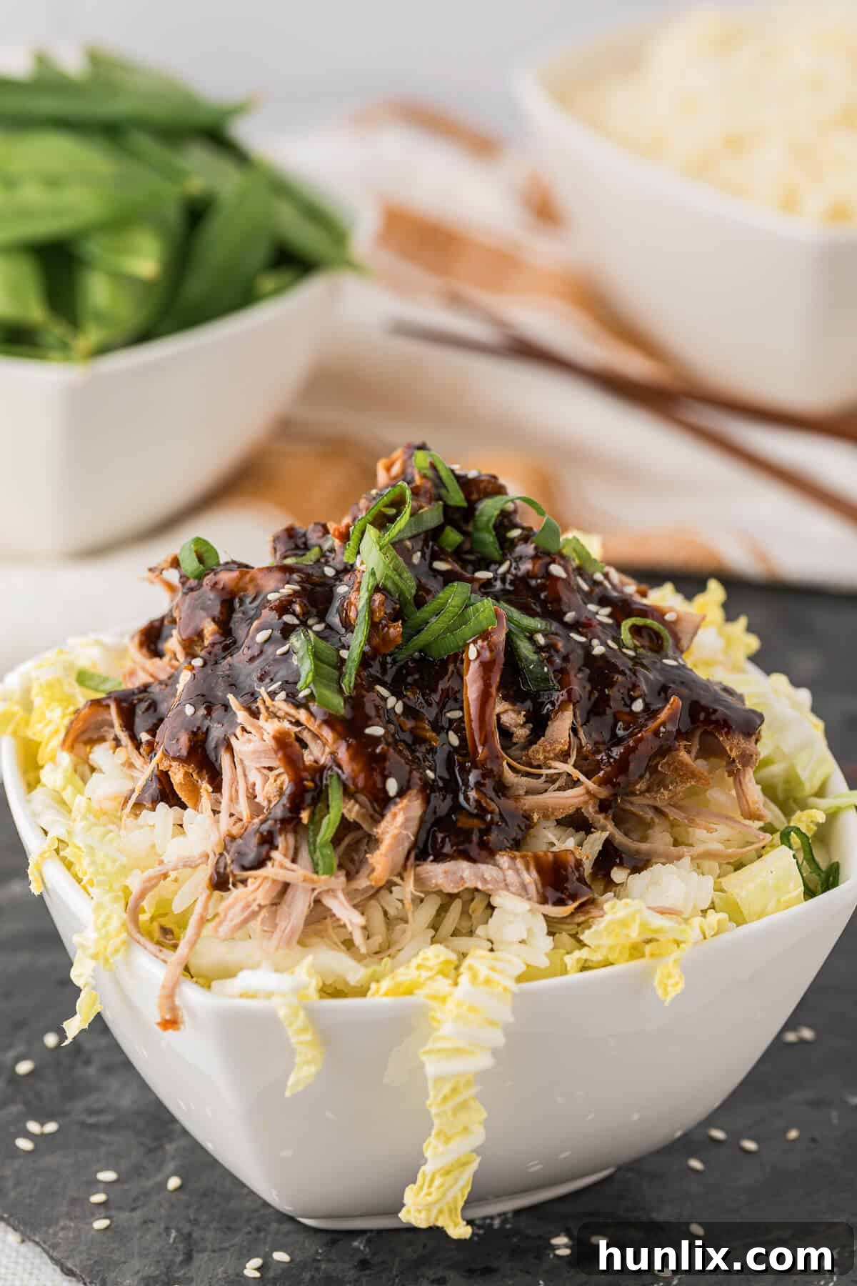 Soy Ginger Pork Tenderloin 6 A bowl filled with white rice, fresh cabbage, and shredded Asian pork tenderloin, ready to serve.